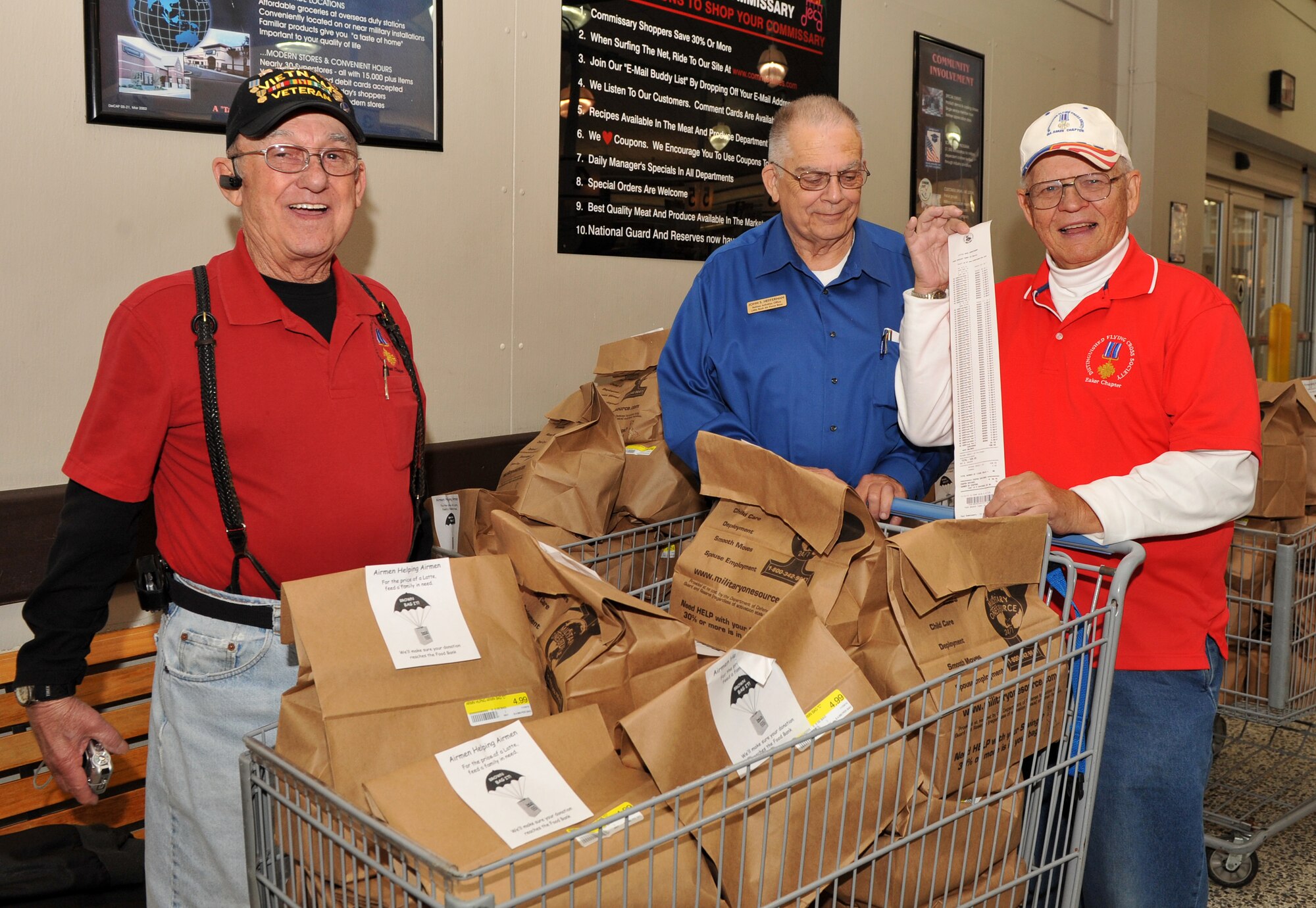 (From left) Gordon Hartley, John Heffernan, and William Kehler, from the Distinguished Flying Cross Society, stand next to 85 bags of groceries they bought for Airmen Helping Airmen Nov. 16, 2010, at the base commissary at Little Rock Air Force Base, Ark. The quarterly Airmen Helping Airmen program helps Team Little Rock families in need. (U.S. Air Force photo by Senior Airman Gul Crockett)