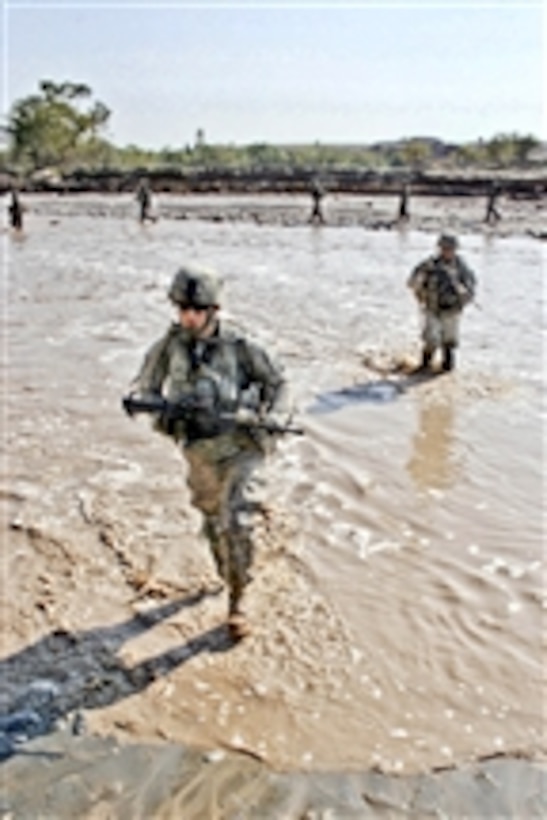 U.S. Army Spc. Jacob Phillips (front) and Spc. Bjorn Goller Hagord cross a river of waist-high muddy water in the Towr Gahr Pass, Nangarhar province, Afghanistan, on Nov. 6, 2010.  Phillips and Goller are assigned to 1st Squadron, 61st Cavalry Regiment.  