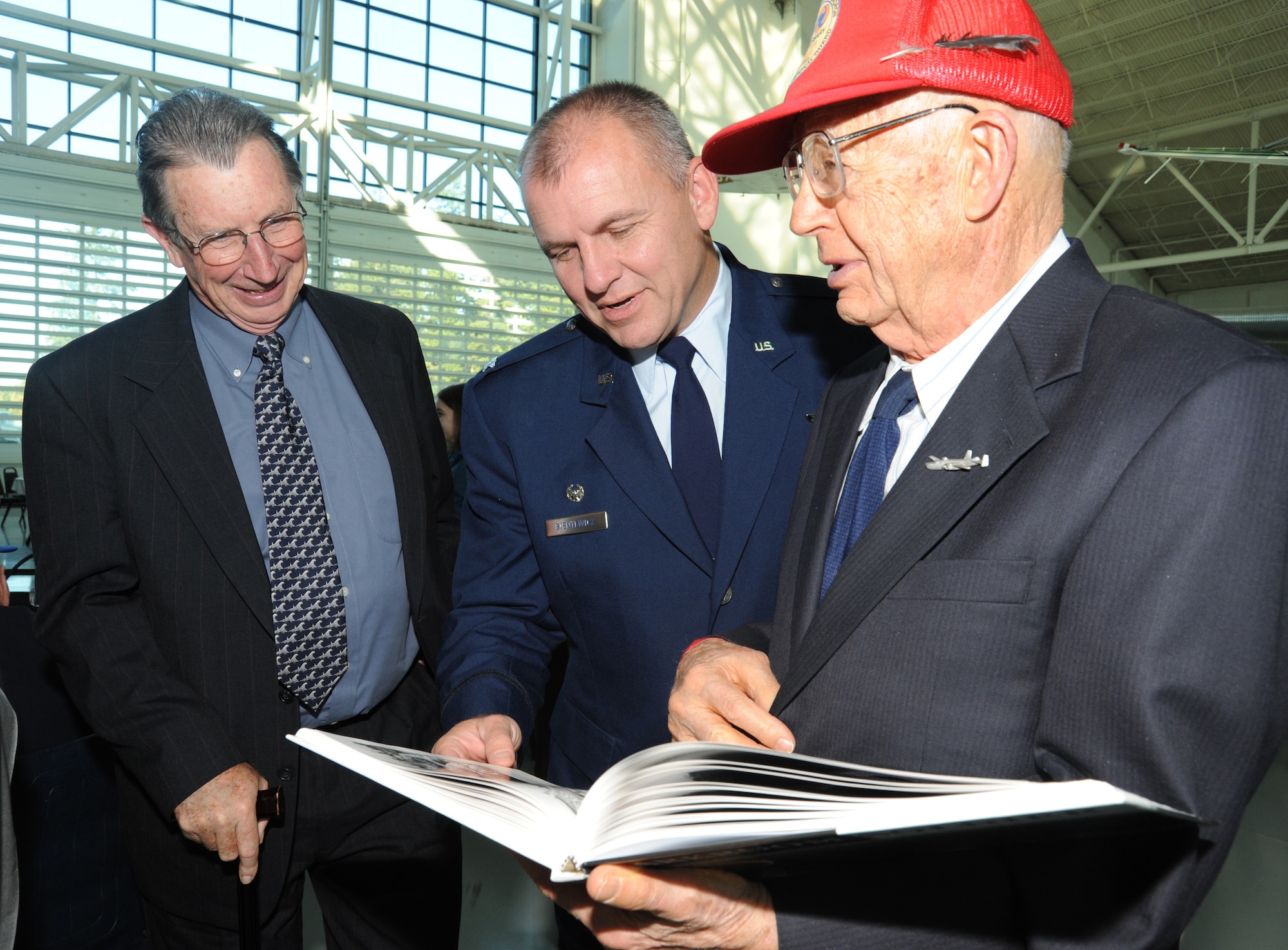Fred Hill shows off his book, "Darkroom Soldier" to Oregon Air National Guard retired Major Gen. David E.B. Ward and 142nd Fighter Wing Commander Michael Bieniewicz after the Hall of Honor induction ceremony held at the Evergreen Aviation and Space museum in McMinnville, Ore., on October 17, 2010. Hill was one of the first members of the 123rd Observation Squardon, which was the first group inducted to the Hall of Honor. (U.S. Photograph by Staff Sgt. John Hughel, 142nd Fighter Wing Public Affairs Department)