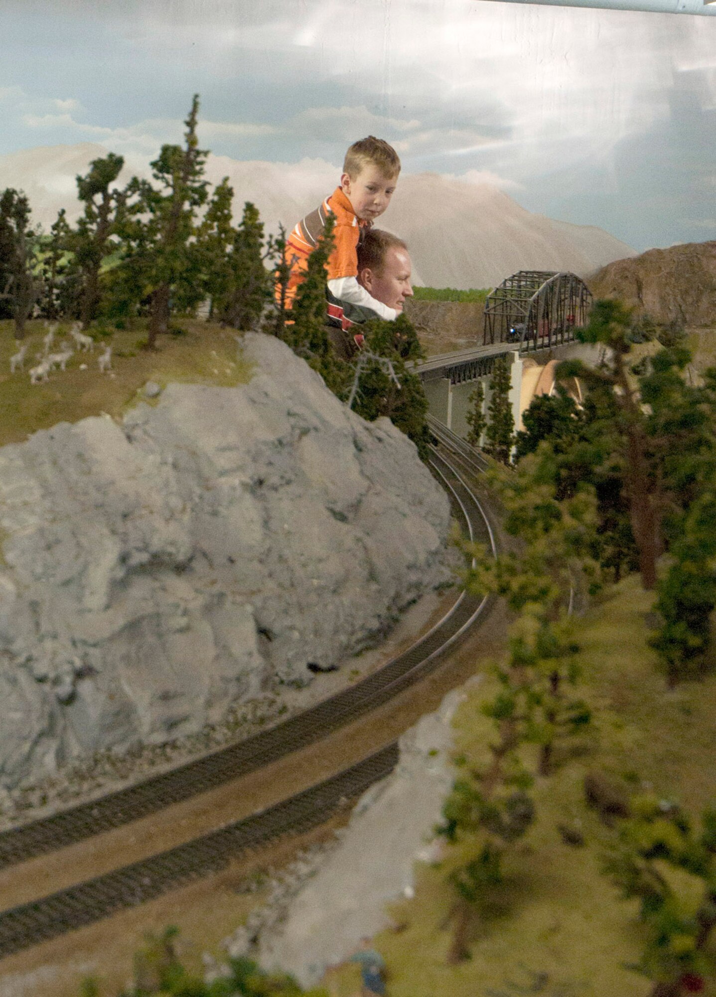 Air Force Staff Sgt. Mike Henrie, U.S. Air Force Band of the Pacific, and son, Sam, watch as a H0 scale model train crosses a scratch-built bridge at the Military Society of Model Railroad Engineers open house. (Photo by Steve White/JBER PAO)