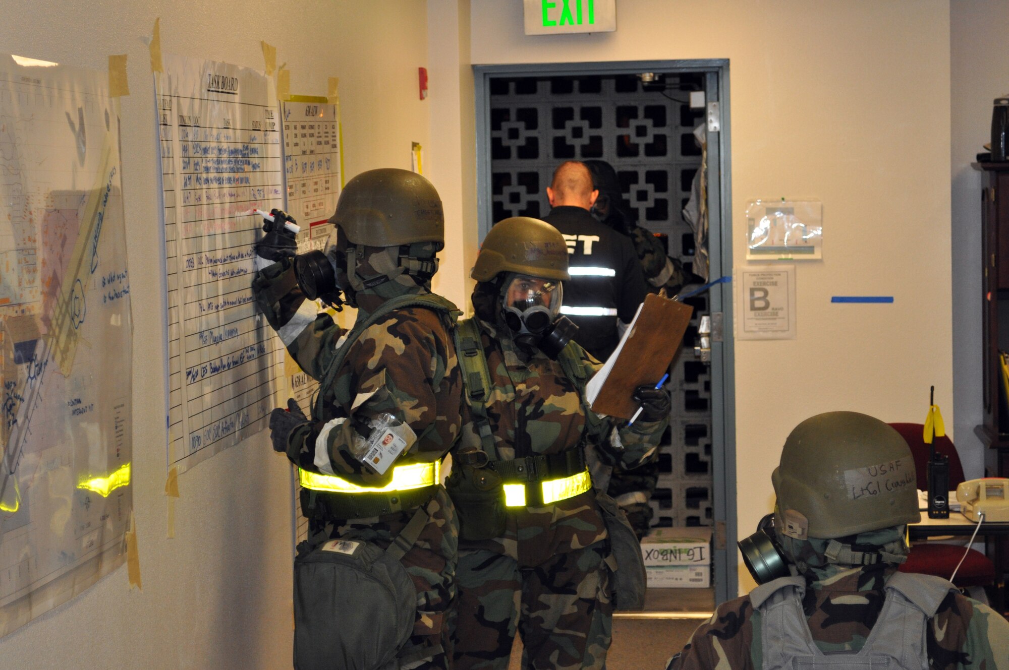 TRAVIS AIR FORCE BASE, Calif. -- The warning has been issued, Airmen have entered Mission Oriented Protective Posture level 4, but the mission goes on, and so does the job. In the night shift Emergency Operations Center, Airmen update the status board, and communicate via voice and phone to continue performing their duties. (U.S. Air Force photo/Senior Master Sgt. Ellen Hatfield)