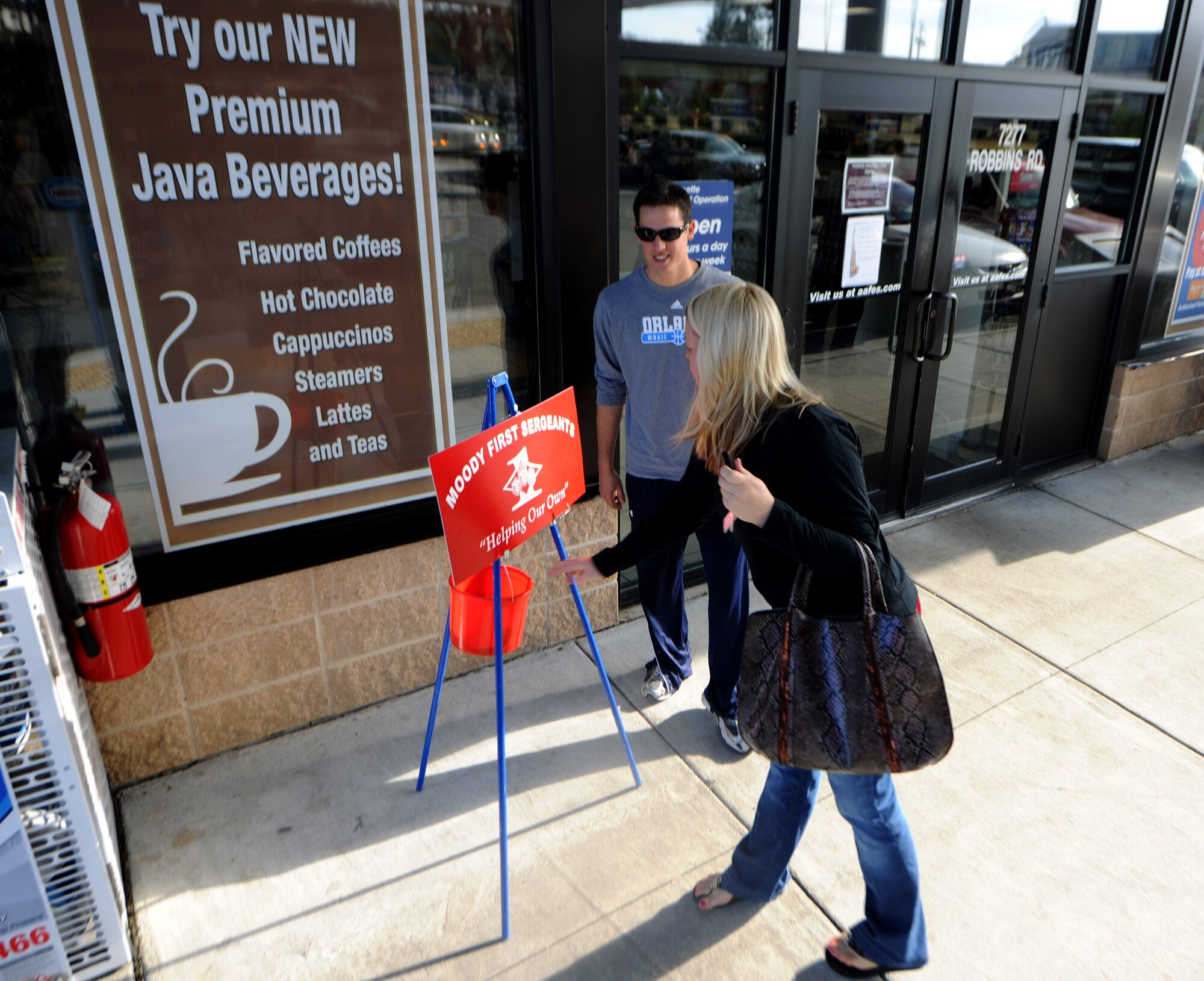 MOODY AIR FORCE BASE, Ga.-- Lorie Solis, military spouse, drops money into the Moody’s First Sergeants Council donation bucket as Airman Ryan Countryman, 23rd Civil Engineer Squadron, rings the bell outside the Shoppette Nov. 23. Airman Countryman is one of several volunteers who assist the First Sergeants Council in raising money. (U.S. Air Force photo/Airman 1st Class Benjamin Wiseman)(RELEASED)