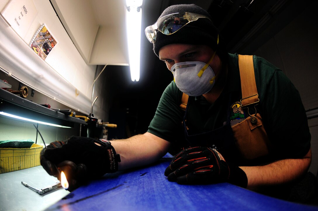 ELLSWORTH AIR FORCE BASE, S.D. - Nate Miller, 28th Force Support Squadron Outdoor Recreation shop technician, melts p-tex thermoplastic into a gouge on the base of a snowboard, Nov. 22.  Outdoor Rec. charges $25 for either ski or snowboard tune-ups. (U.S. Air Force photo/Staff Sgt. Marc I. Lane)