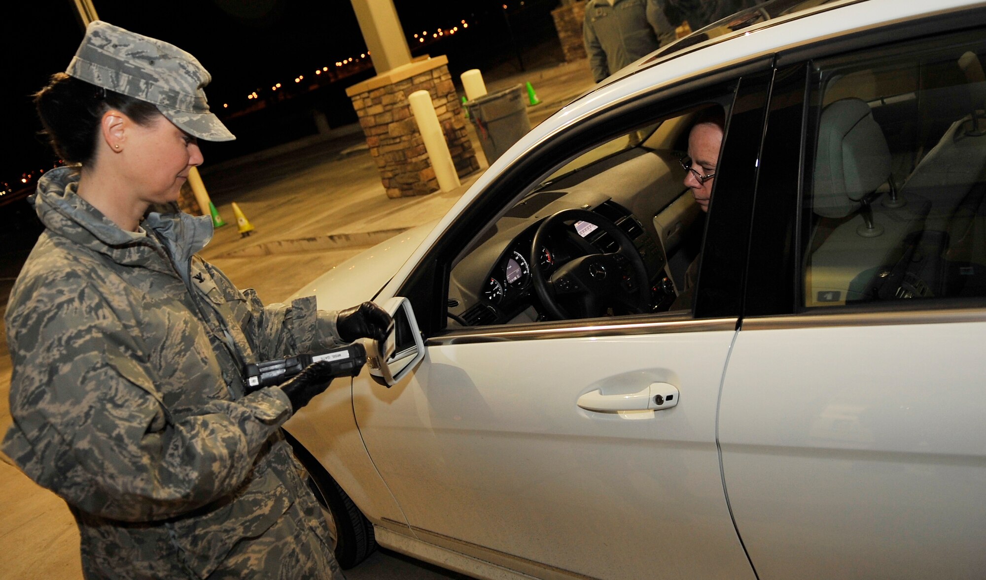 Col. Deirdre Mahon, 460th Mission Support Group commander inspects a ID card as the first cars arrives at the newly opened Mississippi Gate Nov 15, 2010.The new facility provides additional physical and environmental protection measures for the guards. (U.S. Air Force photo by Airman 1st Class Paul Labbe.)