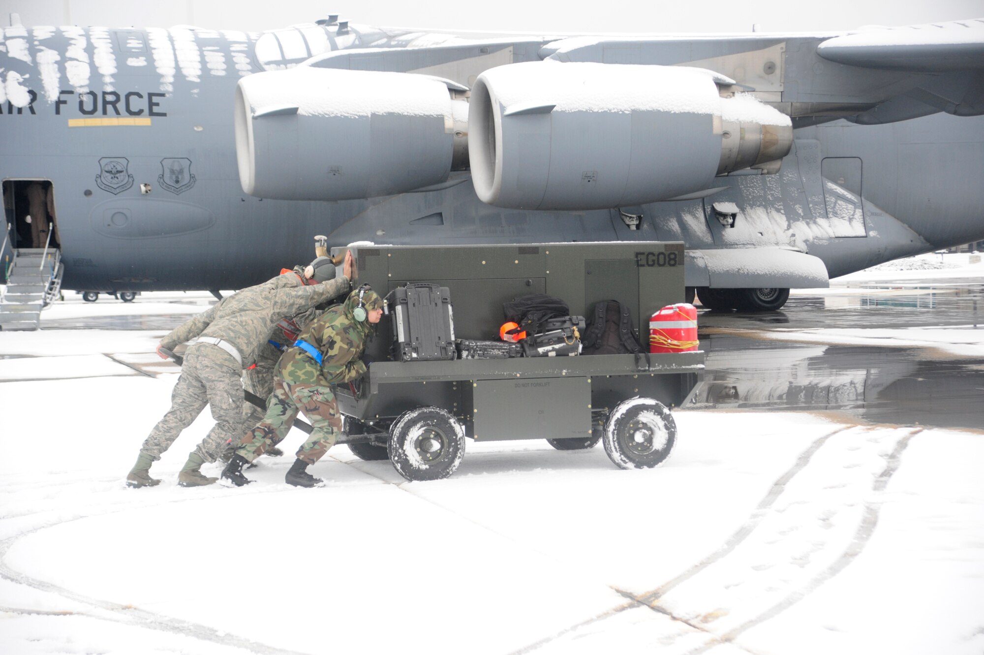 Airmen move a generator into position while servicing a C-17 Globemaster III before a mission Nov. 22, 2010, at Joint Base Lewis-McChord, Wash. More than two inches of snow fell on McChord Field. The Airmen are from the 62nd Aircraft Maintenance Squadron.  (U.S. Air Force photo/Tech. Sgt. Oshawn Jefferson)