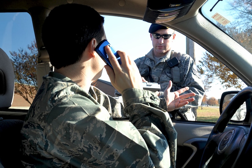 LANGLEY AIR FORCE BASE, Va. -- Staff Sgt. Jeff Tipton, a patrolman with the 633d Security Forces Squadron, simulates writing a cell phone violation ticket to 2nd Lt. John Cooper, 633d Air Base Wing Public Affairs deputy chief, Nov. 23. Using cell phones without hands-free equipment while driving is against base regulation. Military personnel caught breaking this rule will have citations sent to their commanders and first sergeants, and civilian offenders will receive a $106 fine. (U.S. Air Force photo/Staff Sgt. Ashley Hawkins) (RELEASED)