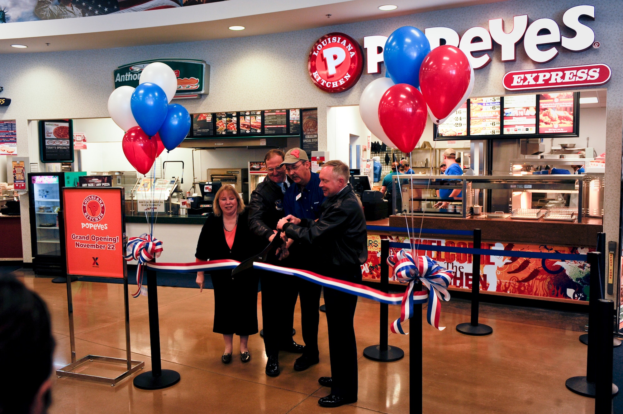 MINOT AIR FORCE BASE, N.D. -- Kathi Zeller, Minot and Grand Forks Exchange general manager, Col. Doug Cox, 5th Bomb Wing command, David Larrison, Minot and Grand Forks Exchange concept manager, and Col. Fred Stoss, 91st Missile Wing commander, cut the ribbon at the grand opening of Popeyes Express in the Exchange food court here Nov. 22. This is the first Popeyes Express in the Army/Air Force Exchange Service and the only one in North Dakota. After three years of planning, coordination and preparation, the new fast food place provides for greater food options on base. (U.S. Air Force photo/Senior Airman Benjamin Stratton)