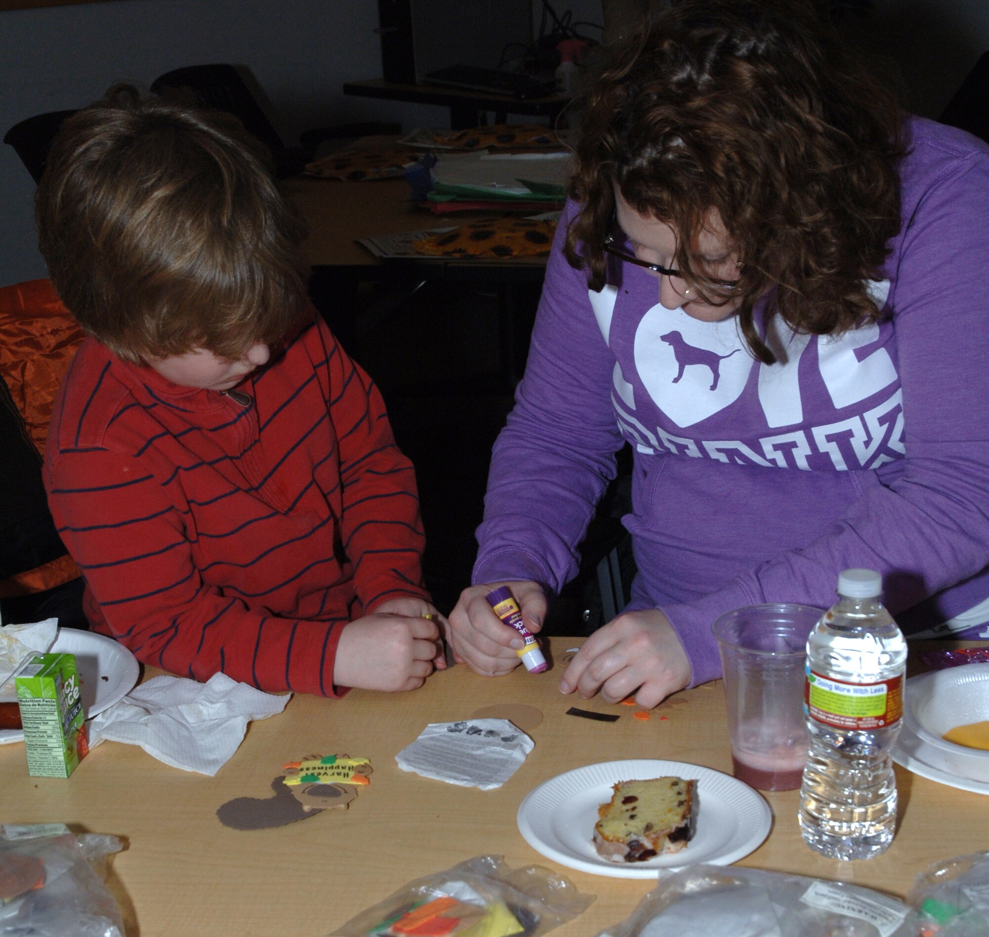 Matthias Mayes (left), watches as his mom, Brandy Mayes, wife of Staff Sgt. Roscoe Mayes, 319th Civil Engineer Squadron, applies glue to a leaf during the 4th Annual Airman and Family Readiness Center Soup Supper, Nov. 23 at the A&FRC. The soup supper is one of the four quarterly open houses the A&FRC hosts to show off the services they provide to both single Airmen and to Airmen with families. The event included ten different homemade soups and stews, desserts, arts and crafts, and a holiday movie. (U.S. Air Force photo by Airman 1st Class Rachel Waller)