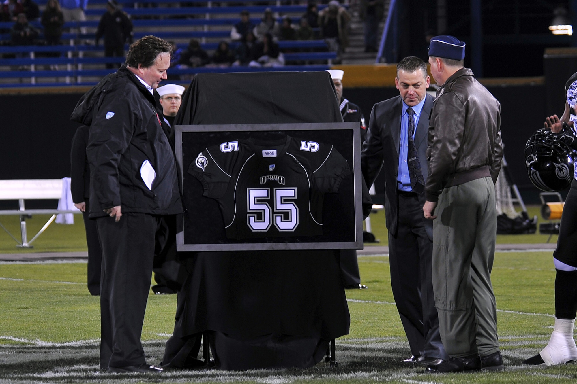 OFFUTT AIR FORCE BASE, Neb. - Don Igo, director of operations for the Omaha Nighthawks, and Rick Mueller, general manager of the Omaha Nighthawks, present a team jersey to Brig. Gen. John N.T. Shanahan during their military appreciation game at the Rosenblatt Stadium Nov. 19. Military members from all branches were celebrated at the game, which ended with a Florida Tuskers win 27 to 10.U.S. Air Force Photo by Charles Haymond (Released)
