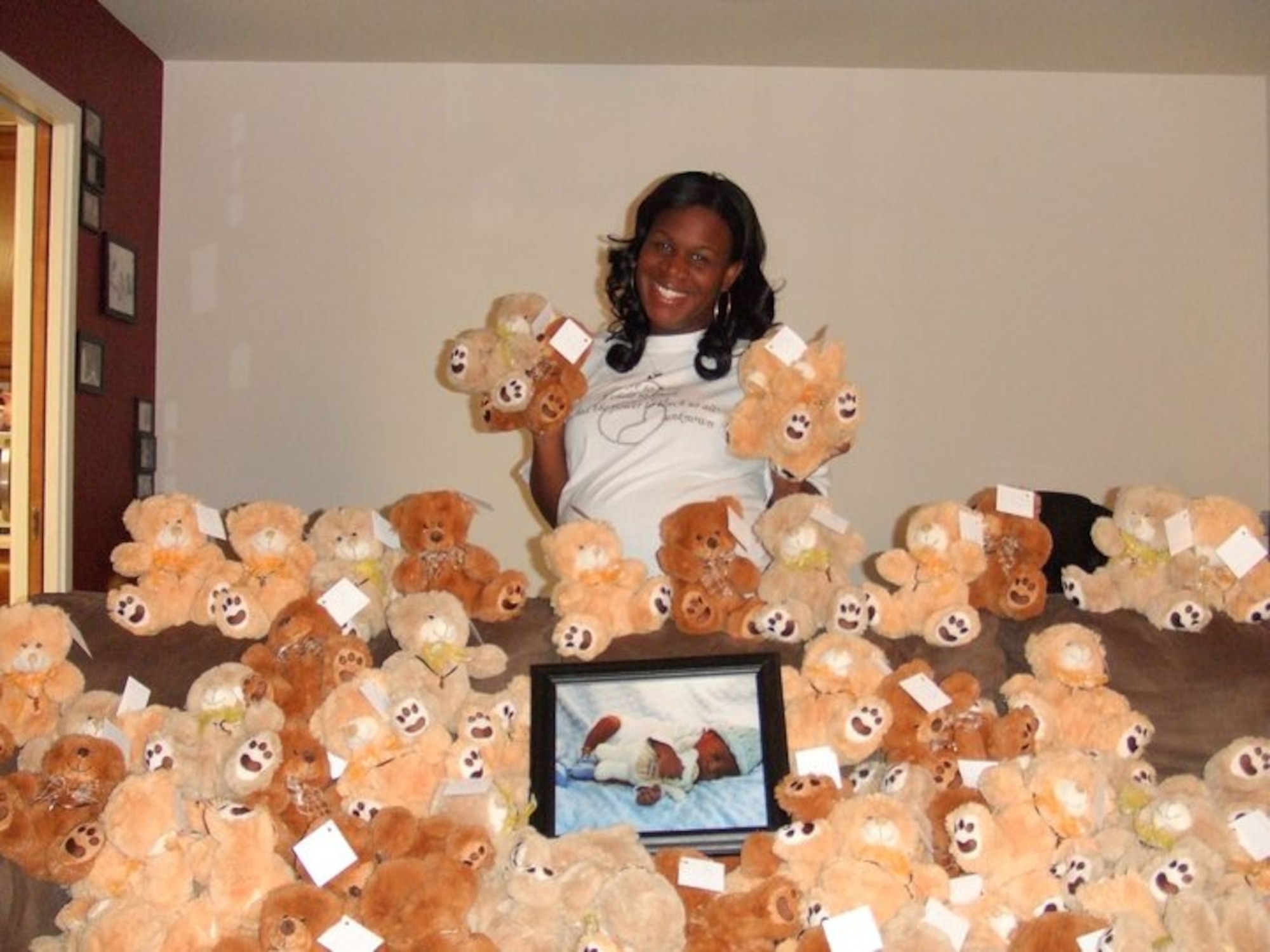 Stephanie Stewart, wife of 552nd Air Control Wing Staff Sgt. Van Stewart, poses with some of the 345 “Angel Bears” she donated to a metro-area hospital from her “My Very Own Angel”?organization. Nestled in the middle of the bears, is a picture of the Stewart’s son Vayden. Vayden died nearly four hours after he was born due to a lower urinary tract obstruction that stopped the development of some of his organs, including his lungs, and hardened his kidneys. Ms. Stewart started the organization to provide resources and support to women and families who have made the decision to carry to term a child with a fatal diagnosis. “I want these women to be able to enjoy their pregnancy and their child the same way anyone else would,” she said. (Courtesy photo)
