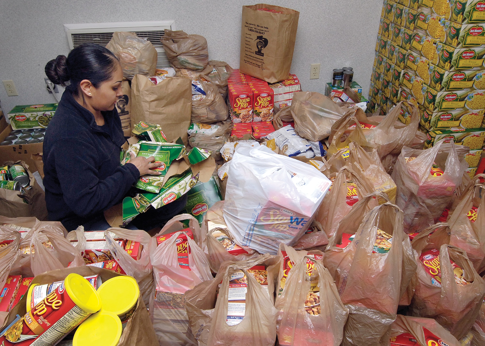 Surrounded by bags of donated food, Staff Sgt. Brenda Robinson, 552nd Operations Support Squadron, breaks down boxes after the canned goods were put in their places. In just 45 minutes on Nov. 19, volunteers from the Air Force and Navy filled 400 bags with food to distribute to military families in need.