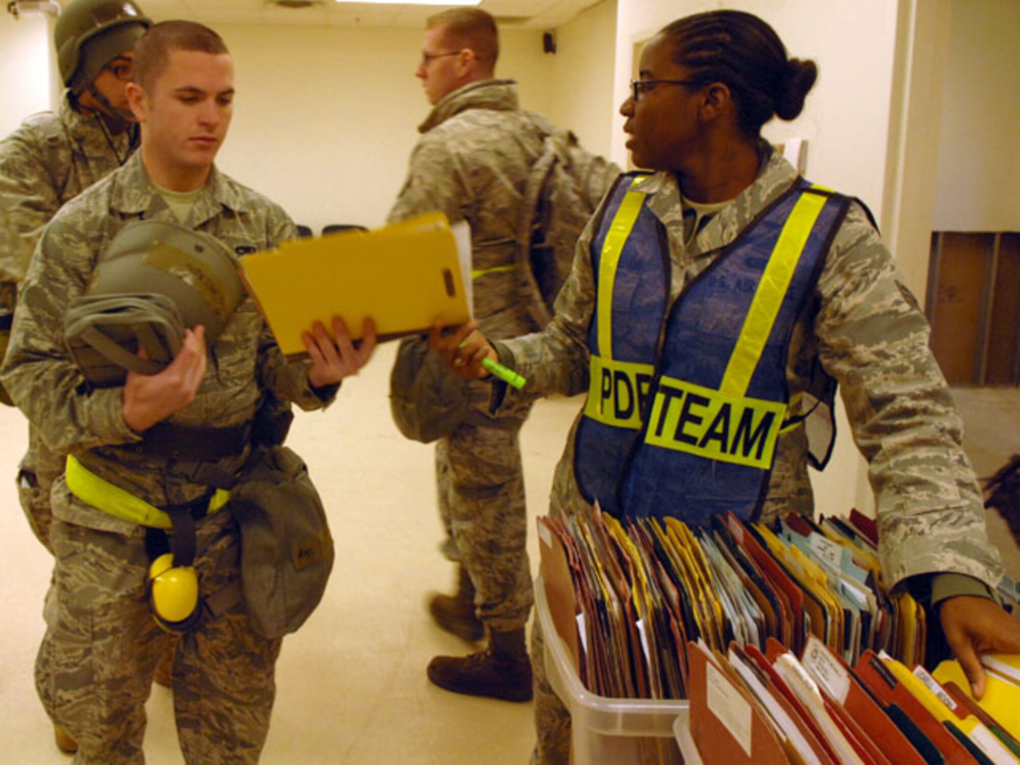 LANGLEY AIR FORCE BASE, Va. – Senior Airman Airene Thomas-Williams, (right),633rd Force Support Squadron, gives Staff Sgt. Xavier Springer, 1st Maintenance Operation Squadron, his mobility folder during a Phase I Operational Readiness Exercise Nov. 19. Wing Exercise Evaluation Team members spent two days assessing the ability of the 633d Air Base Wing, 1st Fighter Wing and 192d Fighter Wing to deploy cargo, aircraft and Airmen within a limited timeframe. (U.S. Air Force photo/ Staff Sgt. Jeff Nevison)(RELEASED)