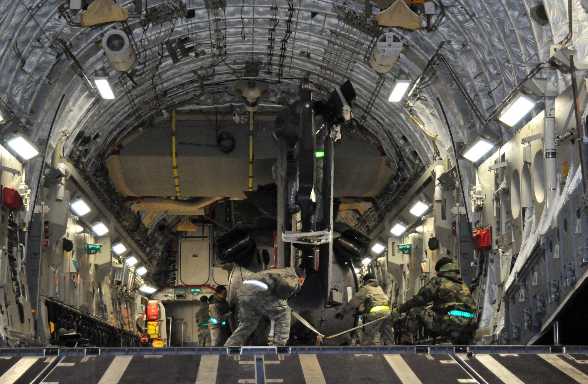 ROYAL AIR FORCE LAKENHEATH, England -- Airmen maneuver an HH-60G Pave Hawk helicopter into place in the cargo bay of a C-17 Globemaster III on Nov. 22. Approximately 20 Airmen from the 748th Aircraft Maintenance Squadron and the C-17’s flight crew worked together to load two helicopters for a deployment to Afghanistan. (U.S. Air Force photo/Senior Airman David Dobrydney)