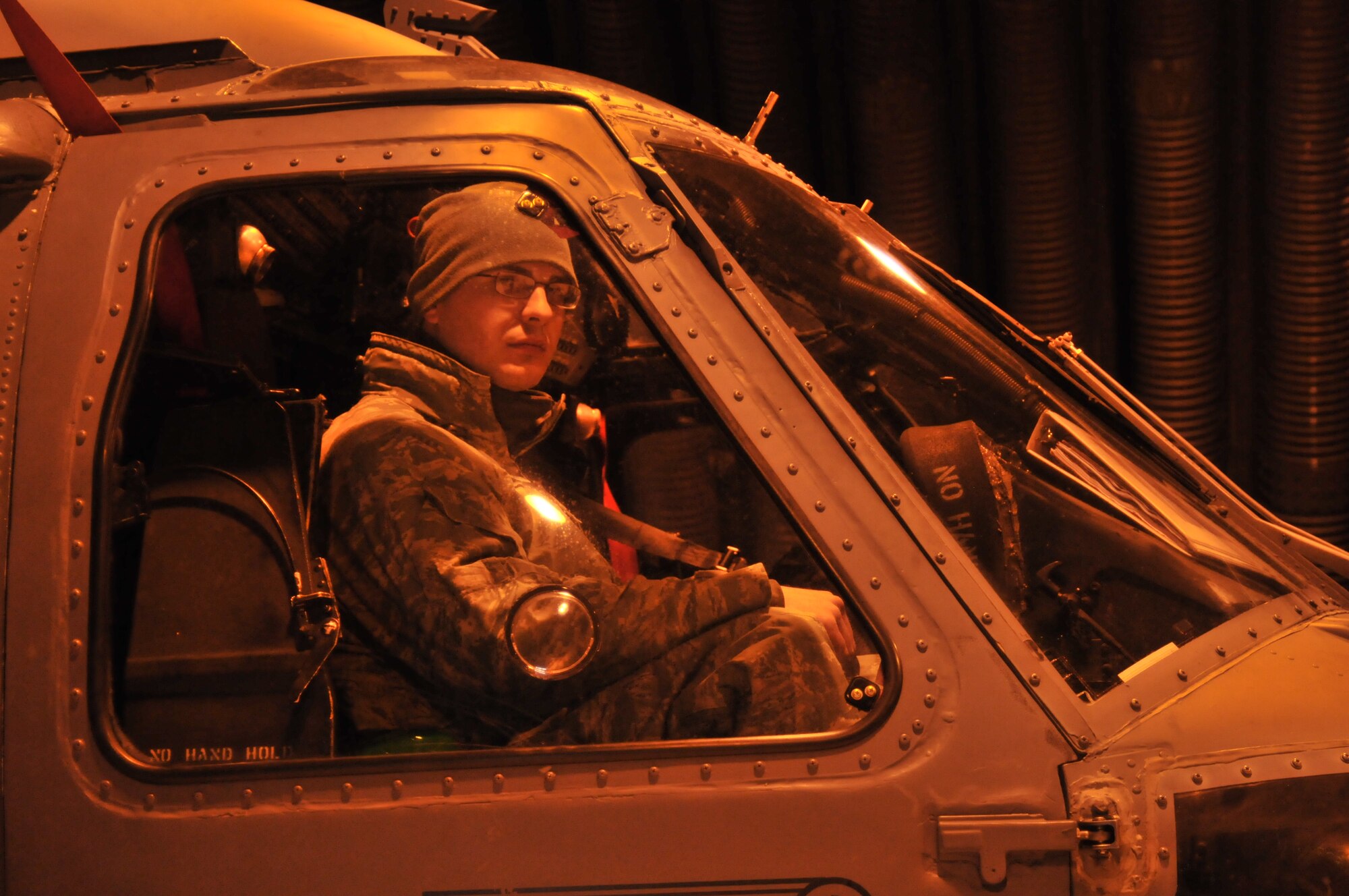 ROYAL AIR FORCE LAKENHEATH, England – Staff Sgt. Steven Smiltneek, 748th Aircraft Maintenance Squadron electrical/environmental systems technician, sits in the cockpit of an HH-60G Pave Hawk helicopter to help guide it as it is towed out of its hangar Nov. 22. The helicopter was towed to a waiting C-17 Globemaster III for transport to a deployed location in Afghanistan. (U.S. Air Force photo/Senior Airman David Dobrydney)