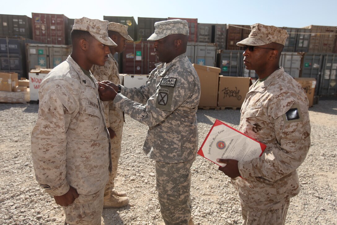 Army 1st Sgt. Evan Unstead, first sergeant of Distribution Company, Brigade Support Battalion, 1st Brigade Combat Team, 10th Mountain Division, pins the Good Conduct Medal on his son, Marine Cpl. Brandon Edgerton, supply warehouse clerk, Medical Logistics Company, Combat Logistics Regiment 15 (Forward), 1st Marine Logistics Group (Forward), at Camp Leatherneck, Afghanistan, Nov. 23. It was a reunion for the father-son duo who hadn’t seen each other since December 2009.