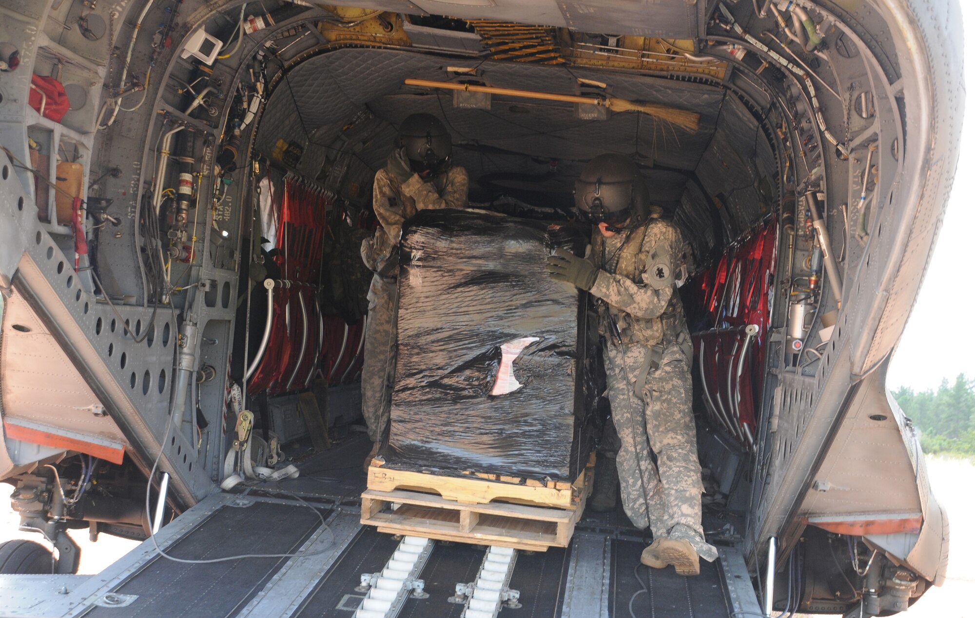 FUERZA MOROCON, Honduras --  Cpl. Brian Godfreaux, left, and Staff Sgt. Jeremy Dudley, both crew chiefs with the 1-228th Aviation Regiment, unload the second pallet of rechargeable batteries from a CH-47 Chinook helicopter here Nov. 23. The 1-228th flew 44 rechargeable batteries to this remote base to ensure the Honduran Infantry Battalion has power during the night. (U.S. Air Force photo/Tech. Sgt. Benjamin Rojek)