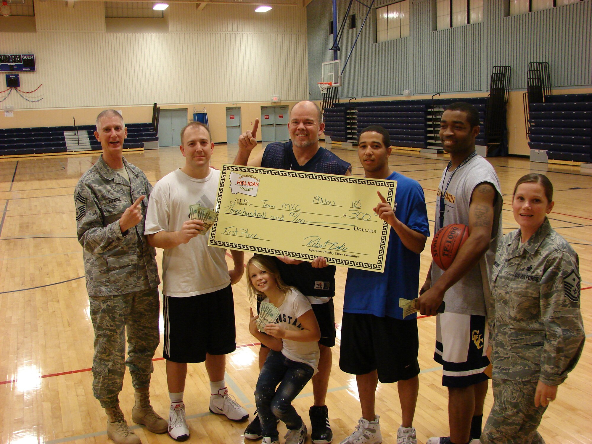 Chief Master Sgt. Craig Fitzkee (left) and Master Sgt. Sheila Lawson (right) are photographed with the first place 3-on-3 basketball team who won $300 during the Operation Holiday Cheer tournament held Nov. 19. Team members from left to right are Tech. Sgt. Martin Cunningham, Stewart Reynolds, and Airmen 1st Class Michael Williams and Maurice Stallion. (Courtesy photo)