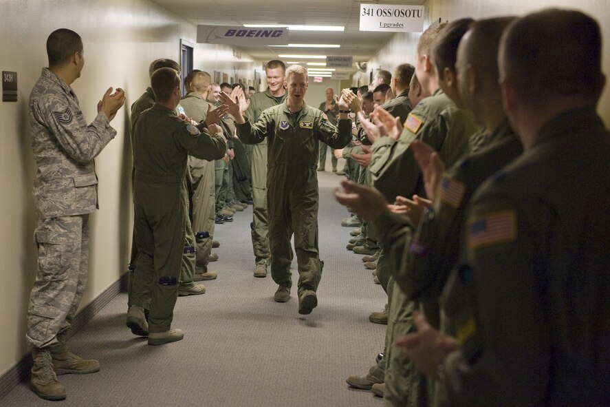 Capt. Kevin Hullihan (front) and 1st Lt. Brian Marlow get good luck high-fives from co-workers before entering the missile procedures trainer for their operations competition in this inaugural Global Strike Challenge. The pair found out last week that they scored the highest in emergency war orders and were presented with the Neary Trophy for their accomplishments. (U.S. Air Force photo/Beau Wade)