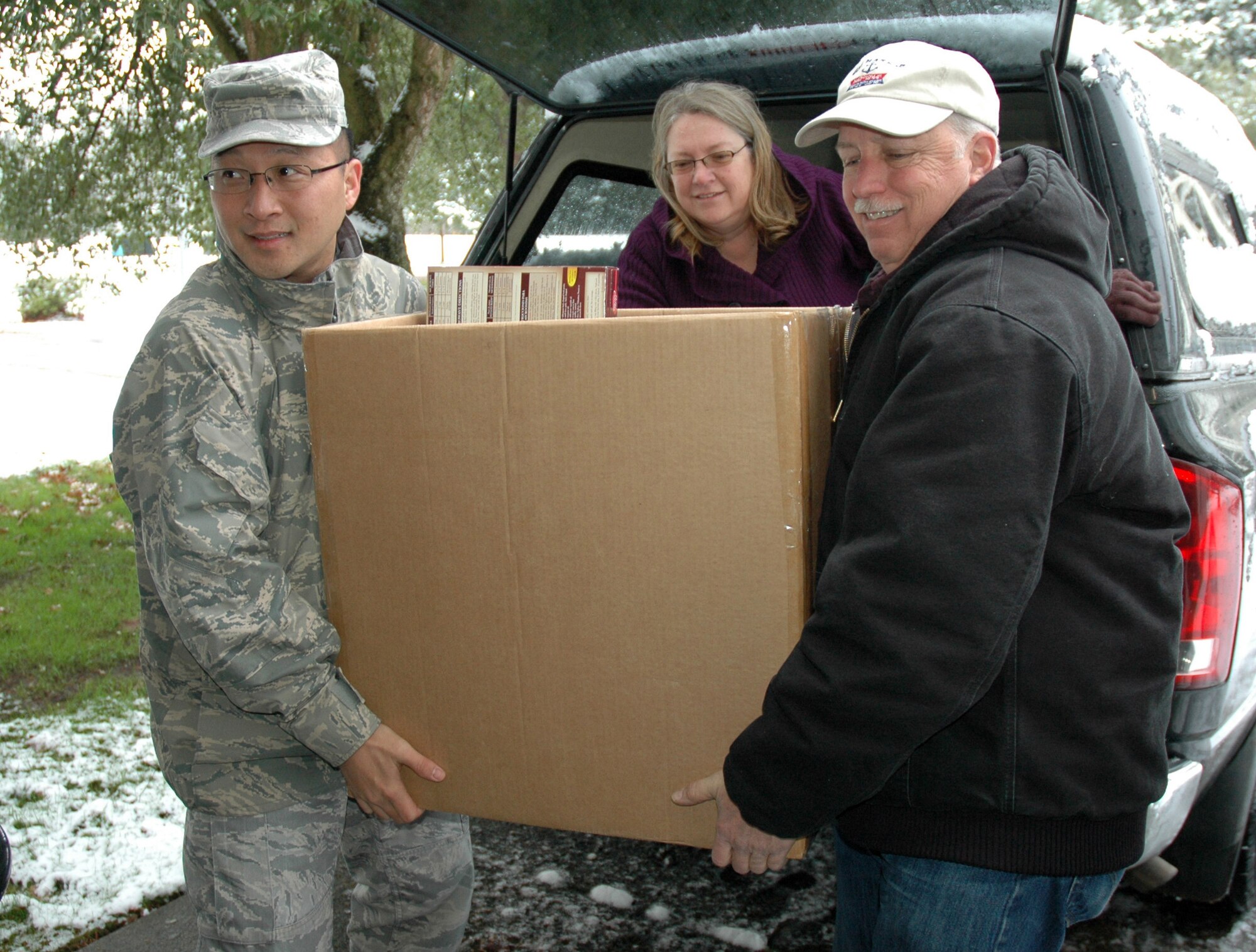 JOINT BASE LEWIS-MCCHORD, Wash.- Senior Master Sgt. Tung Yoga Monroe, left, 446th Aircraft Maintenance Squadron, Balinda Cargill, 446th Aircraft Maintenance Squadron administrative assistant, and Master Sgt. Gary Davis, 446th Aircraft Maintenance Squadron crew chief, carry a box of food donated from the USO to the Airmen and Family Center, Nov. 22, for the wing Care and Share Program. This is just the beginning of many future involvements the 446th AMXS Top 3 will be participating in on base and in the community as part of their leading by example focus.  Top 3 members plan to help Airmen and Family Readiness during Christmas and with Habitat for Humanity in Pierce County, Wash. (U.S. Air Force photo/Master Sgt. Jake Chappelle)