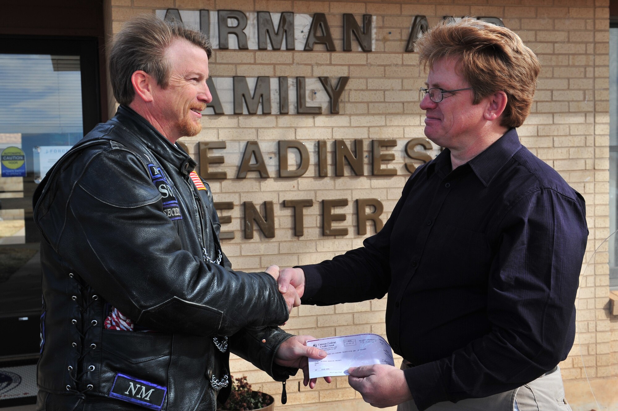 Michael King, 27th Special Operations Group and member of Americas Guardians motorcycle club presents John Fondrick, 27th Special Operations Force Support Squadron, with a check for $1,635.18 at Cannon Air Force Base, Nov 24, 2010. The donation goes to Friends of Family Support and in turn into a local wounded warrior fund. The local chapter of Americas Guardians in Clovis and Portales consists of veterans and first responders. (U.S. Air Force photo by Tech Sgt. Josef Cole)(RELEASED)