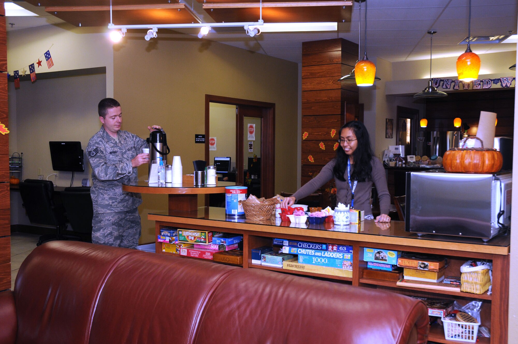 Angela Delos Santos, a Delaware USO volunteer, restocks coffee for Airmen like Staff Sgt. Blazej Masiak, 436th Aerial Port Squadron, inside the USO Community Center, Dover Air Force Base, Del. Nov. 23, 2010. The center, inside the passenger terminal, offers free coffee and snacks for travelers and base members daily. (U.S. Air Force photo by Senior Airman Jessica Cendana /Released)