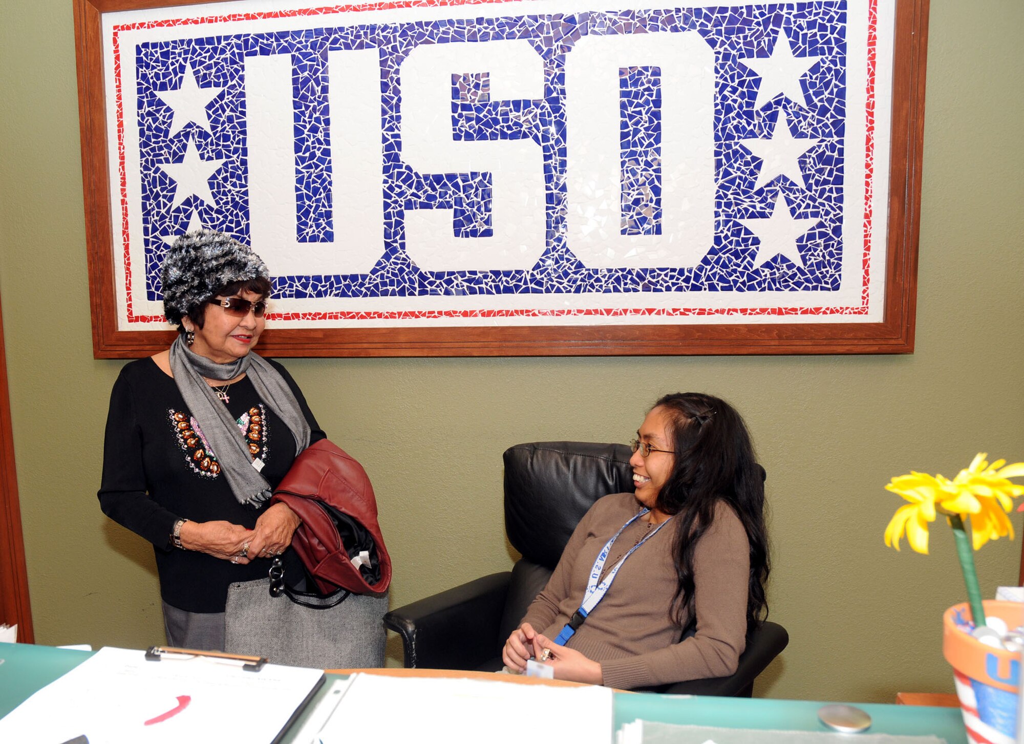 Delaware USO volunteers Gloria Leet (left) and Angela Delos Santos talk at the front desk of the USO Community Center, Dover Air Force Base, Del., Nov. 23, 2010. Some USO volunteer duties include organizing USO care packages and providing directions to local attractions. (U.S. Air Force photo by Senior Airman Jessica Cendana /Released) 