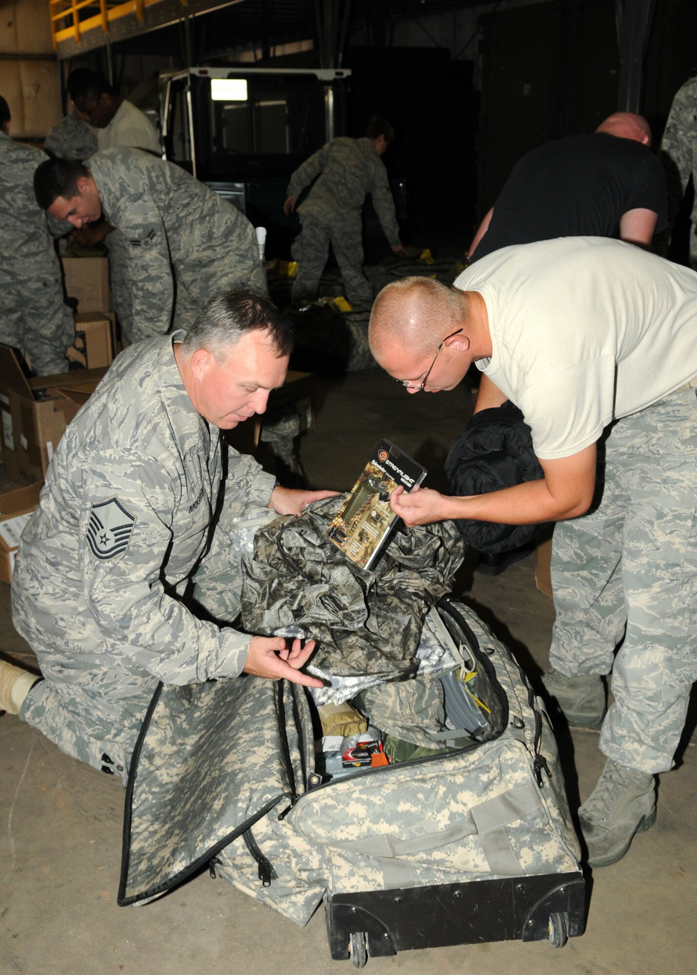 Master Sgt. James Mogren assists a defender, who is about to deploy, with verifying the required items are in his issued mobility bag. (Courtesy photo)