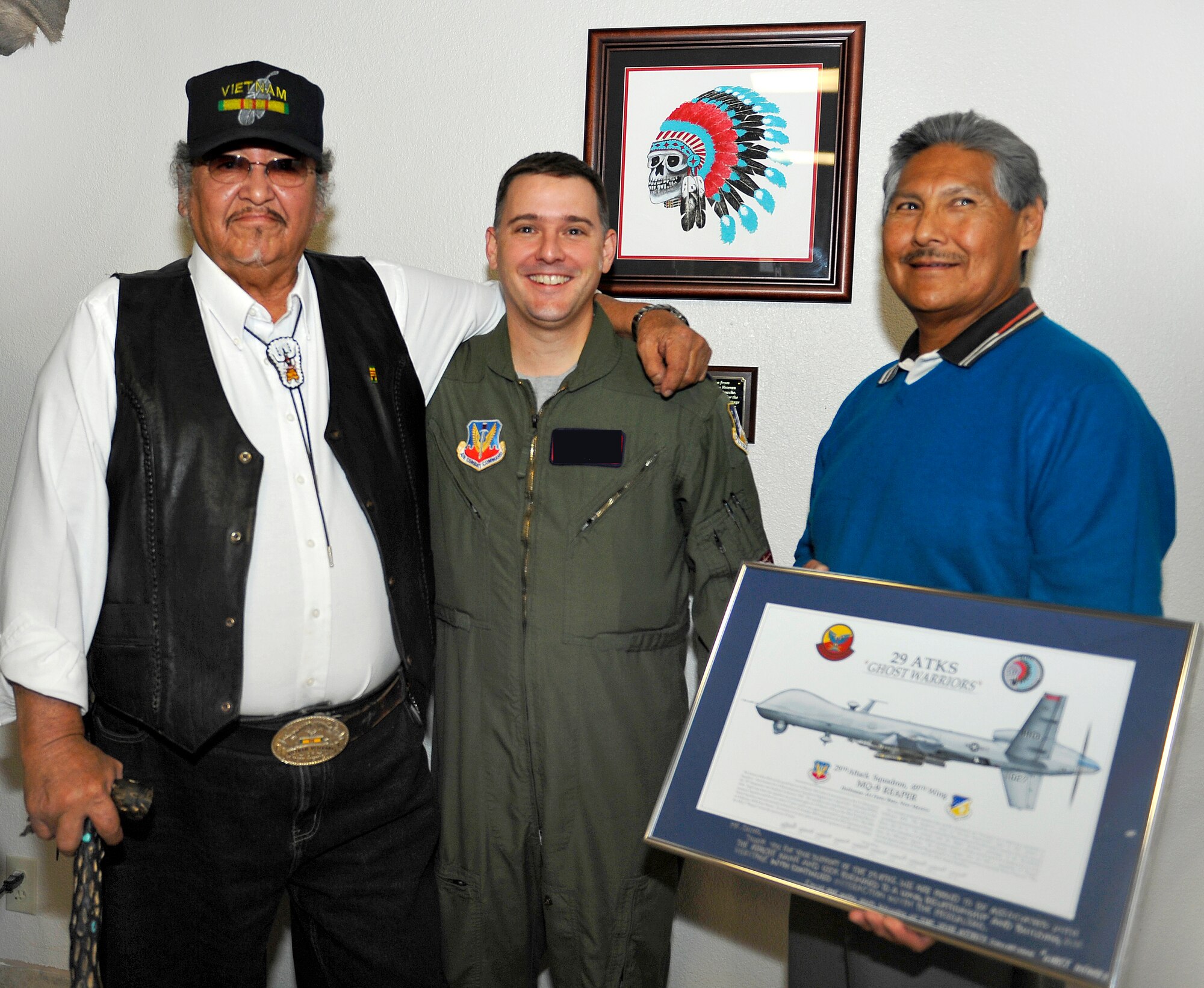 HOLLOMAN AIR FORCE BASE, N.M. -- Gervase Peso, Vietnam Veteran and member of the Mescalero Apache Tribe, poses with a Lieutenant Colonel from the 29th Attack Squadron and Mark Chino, president of the Mescalero Apache Tribe, during the grand opening of the heritage room Nov. 19, 2010. Mr. Peso's artwork is showcased on the wall specifically for the 29th ATKS "Ghost Warriors" to affirm heritage associated with the reactivation of the squadron on 23 October 2009 at Holloman. President Chino was presented with an MQ-9 Reaper photograph in dedication of his support and continued relationship with the squadron. The ceremony kicked off with food and drinks followed by a blessing of a Remotely Piloted Aircraft made significant with a tribal chant that also honored famous Apache leaders such as Geronimo and Chochise. (U.S. Air Force photo by Senior Airman Veronica Stamps/Released)