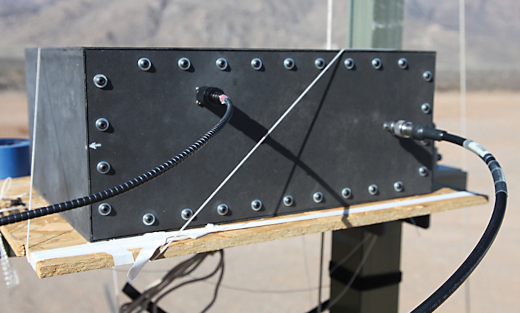 Working to minimize air vehicle vulnerability to electromagnetically or radio-frequency-induced damage, AFRL performed high-power microwave testing of this nickel nanostrand composite electronics enclosure (pictured with ultradense alignment-tolerant fiber-optic cable attached), which will undergo additional examination as a candidate technology. (AFRL image)