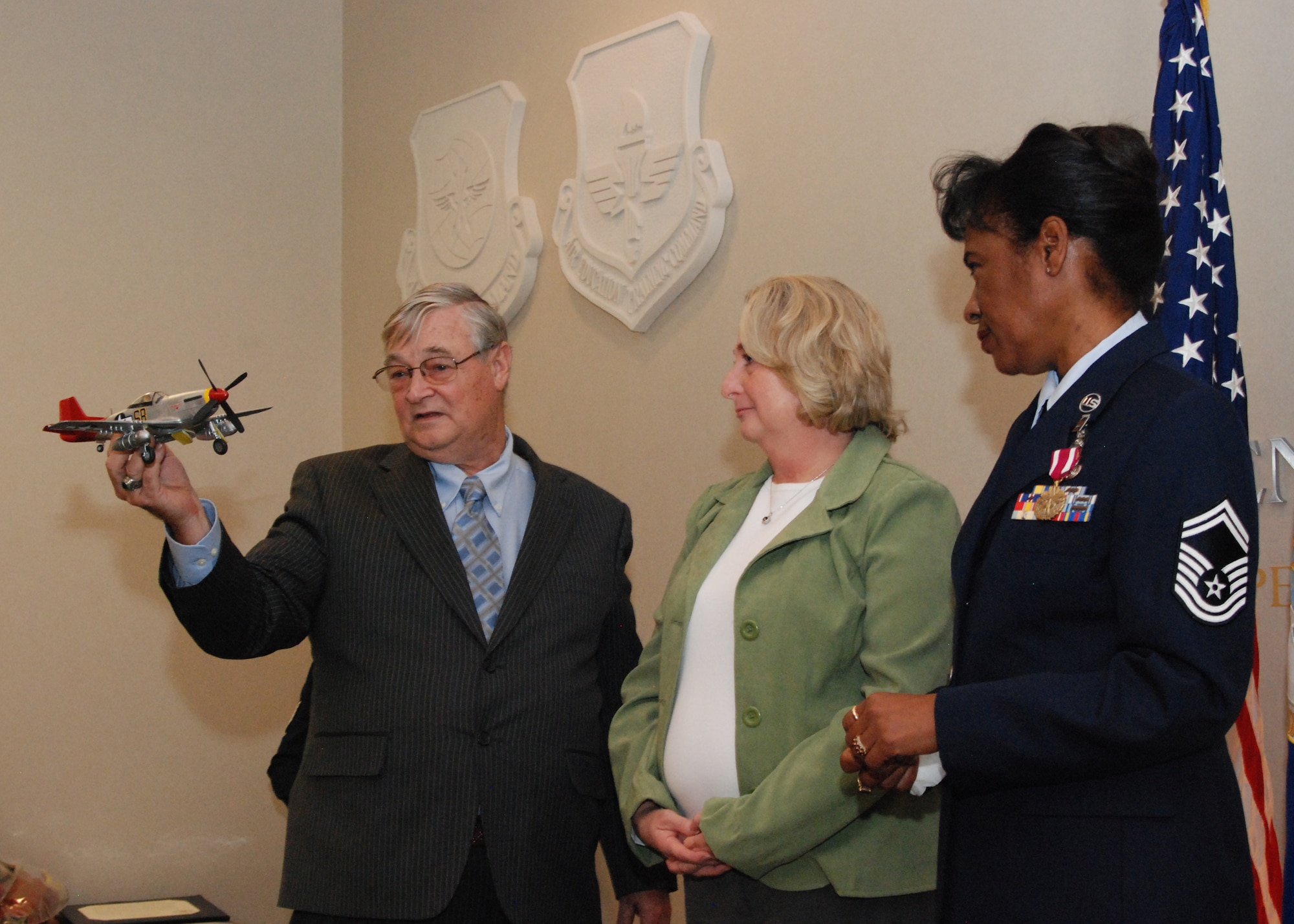 Retired chief master sergeants, Jim and Linda Ersery, present a model of a red-tailed P-51 Mustang to Senior Master Sgt. Sherry Taylor during her retirement ceremony Nov. 6.  Sergeant Taylor’s father—Maj. Clyde Cullen Long, Jr.—was a Tuskegee Airman who was trained as a P-51 Mustang pilot during World War II and flew missions in the aircraft during the Korean War. (U.S. Air Force photo/Master Sgt. Stan Coleman)  