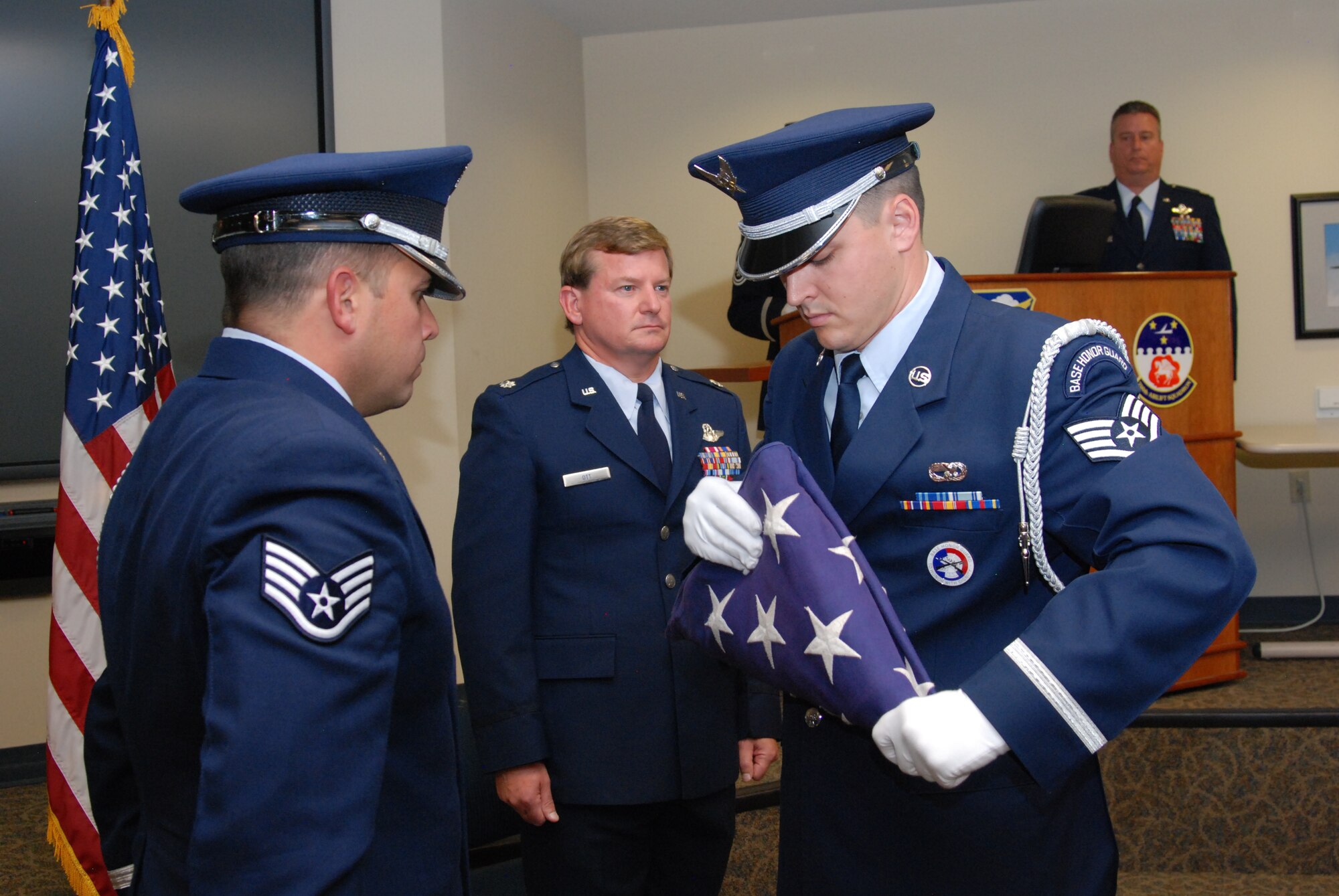 Staff Sgts. Joseph Saldivar and Aaron Abshire, Dobbins Air Reserve Base Honor Guard, perform the American Flag folding and dressing sequence during the retirement ceremony of Lt. Col. Mark Ott, 700th Airlift Squadron evaluator and pilot.  (U.S. Air Force photo/Master Sgt. Stan Coleman)  