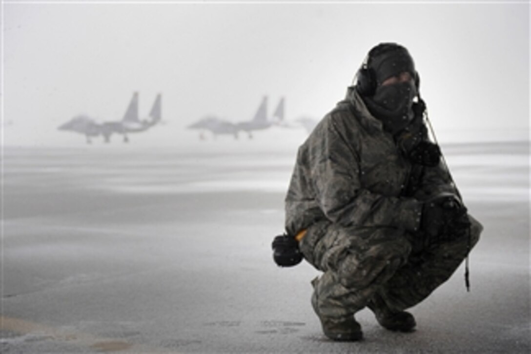 Senior Airman Stephen Held, a crew chief with the 391st Fighter Squadron, takes a break under an aircraft to hide from the snow during an exercise on the flight line at Mountain Home Air Force Base, Idaho, on Nov. 21, 2010.  
