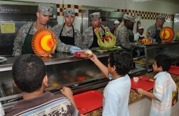 SOTO CANO AIR BASE, Honduras --  Working as a team, Command Sgt. Maj. Alvin Thomas, Lt. Col. James Kanicki and Command Sgt. Maj. Lucio DeAnda serve up a plat of Thanksgiving food to some family members here Nov. 25. Base leaders and other volunteers took turns serving holiday fair to Team Bravo during the lunch meal. (U.S. Air Force photo/Tech. Sgt. Benjamin Rojek)