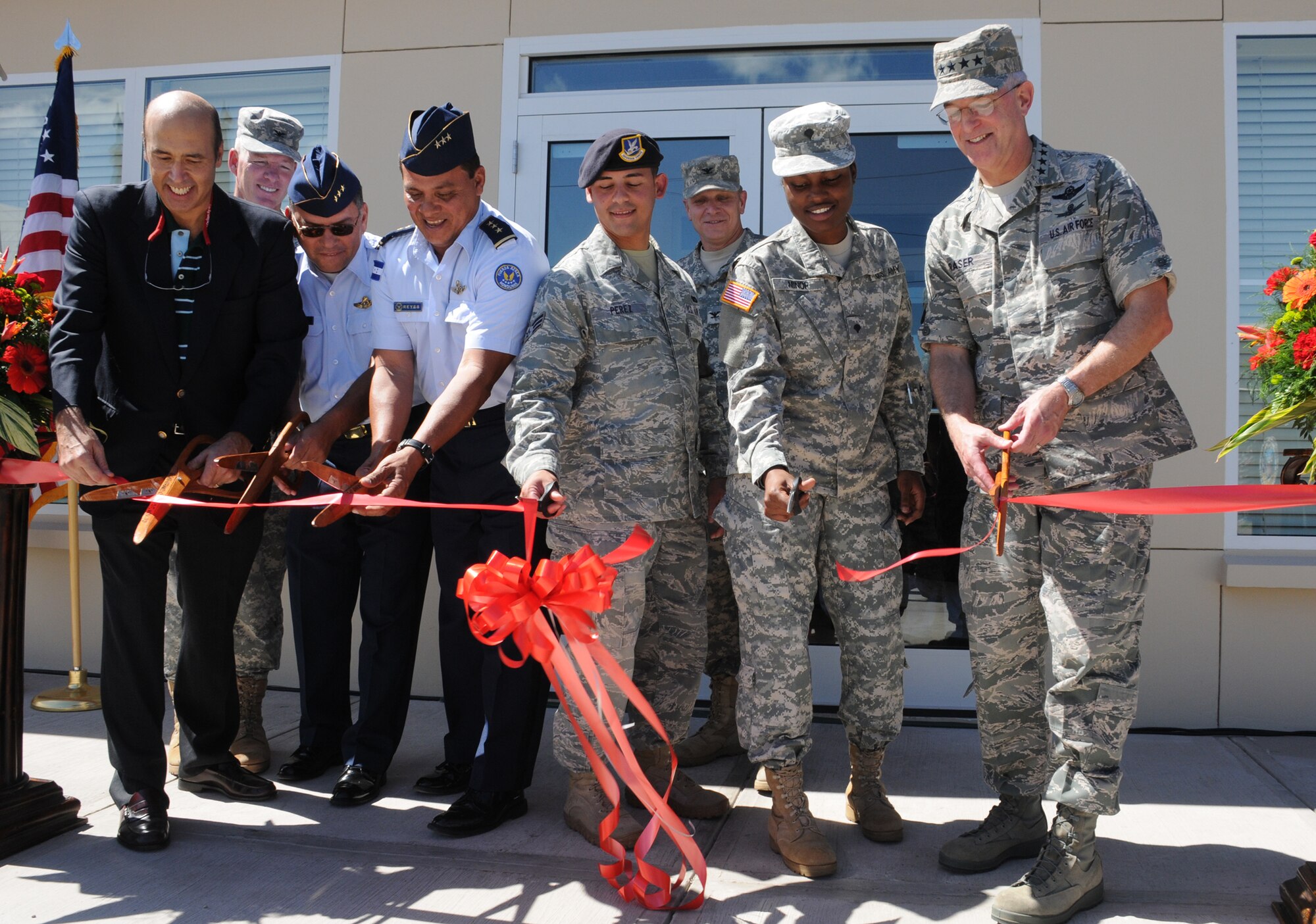 SOTO CANO AIR BASE, Honduras --  (From left) U.S. Ambassador Hugo Lorens, Col. Gregory Reilly, Col. Ruis Landa Dubon, Col. Wilfredo Reyes, Senior Airman Jaime Perez, Col. Martin Clausen, Spc. Jocelyn Minor and Gen. Douglas Fraser all take part in cutting the ceremonial ribbon during the grand opening ceremony of the new dining facility here Nov. 25. (U.S. Air Force photo/Tech. Sgt. Benjamin Rojek)