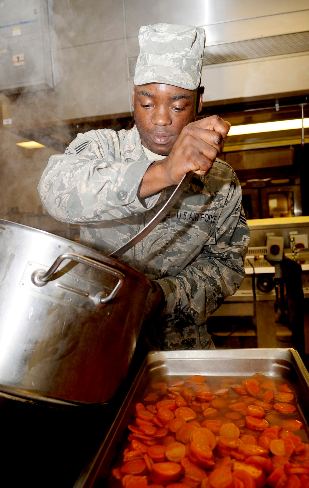 RAF MILDENHALL, England -- Senior Airman Ebot Leonel, 100th Force Support Squadron food specialist, pans glazed carrots after being cooked for the Gateway Dining Facility Thanksgiving dinner Nov. 25, 2010. The carrots are put in pans to save production time and make them easier to be served when the time comes. (U.S. Air Force photo/Senior Airman Ethan Morgan)