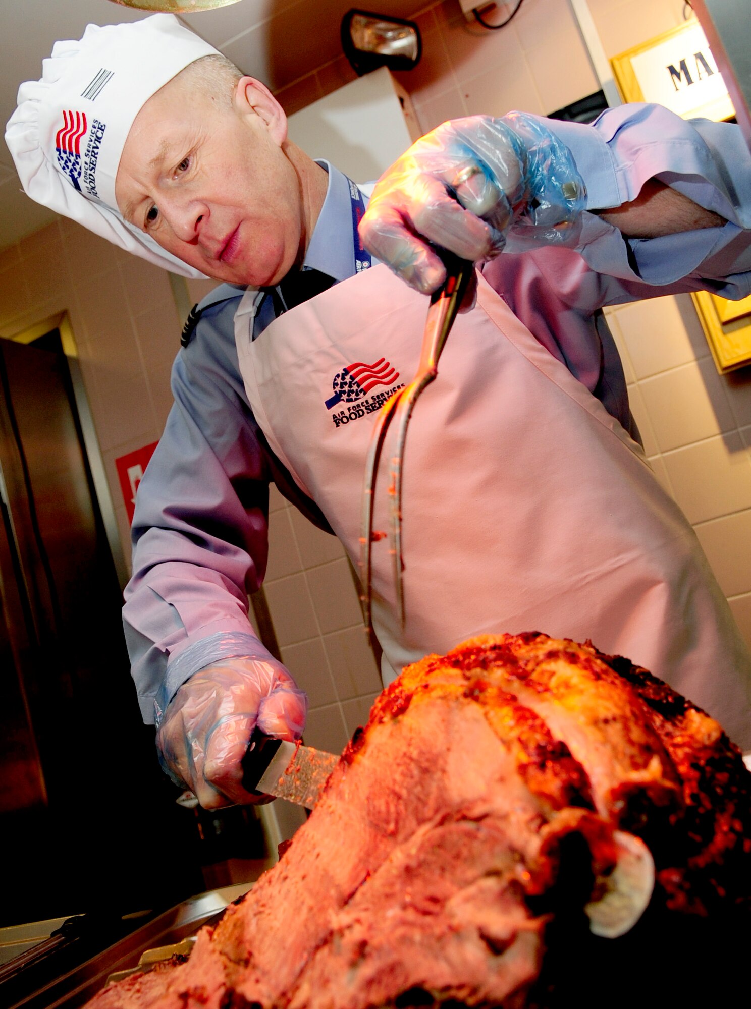 RAF MILDENHALL, England -- Sqdn. Ldr. Rick Fryer, RAF Mildenhall station commander, carves roast beef for Airmen during the Gateway Dining Facility Thanksgiving dinner Nov. 25, 2010. Squadron Leader Fryer said that by serving the Team Mildenhall Airmen not only did it build our international relationship but also gave him the chance to give back to the Airmen at RAF Mildenhall on one of their biggest holidays. (U.S. Air Force photo/Senior Airman Ethan Morgan)