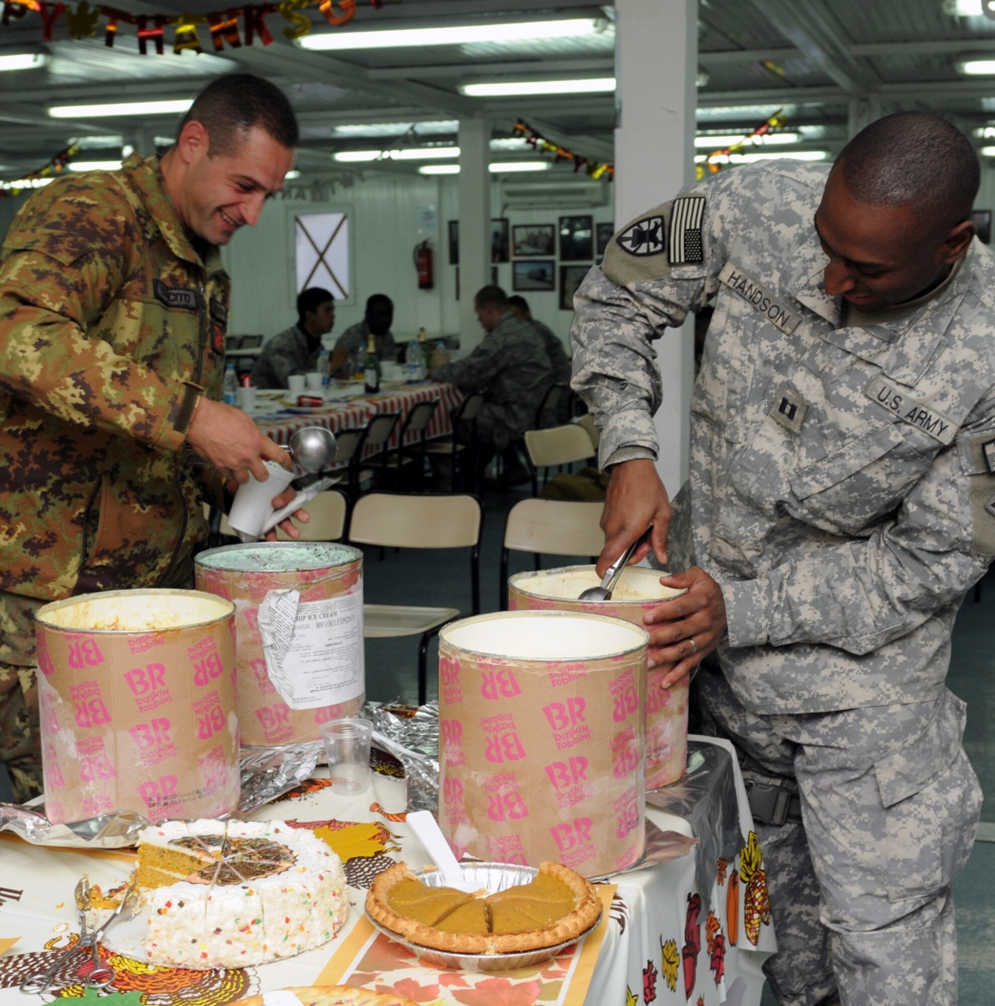 Italian Army Sgt. Vincenzo Abagnale and U.S. Army Capt. Tywin Handson scoop their servings of ice cream after a Thanksgiving dinner at Camp Arena, Herat province, Afghanistan, Nov. 25. In effort to capture the feeling of Thanksgiving, a group of servicemembers convoyed out to a mostly-American staffed base elsewhere in Herat province, and returned to Camp Arena with containers of turkey, mashed potatoes and all the other traditional Thanksgiving luxuries. (U.S. Air Force photo/Tech. Sgt. Kevin Wallace)