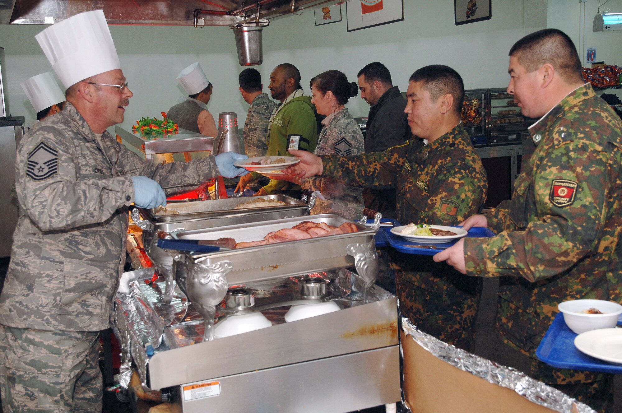 TRANSIT CENTER AT MANAS, Kyrgyzstan - Koi-Tosh Non-Commissioned Officers' Academy are served lunch at the Ala' Too Dining Facility at the Transit Center at Manas Nov. 25.  They received a tour of the Center and ate lunch with the troops in celebration of Thanksgiving Day. (U.S. Air Force photo/Master Sgt. Paul Cox)