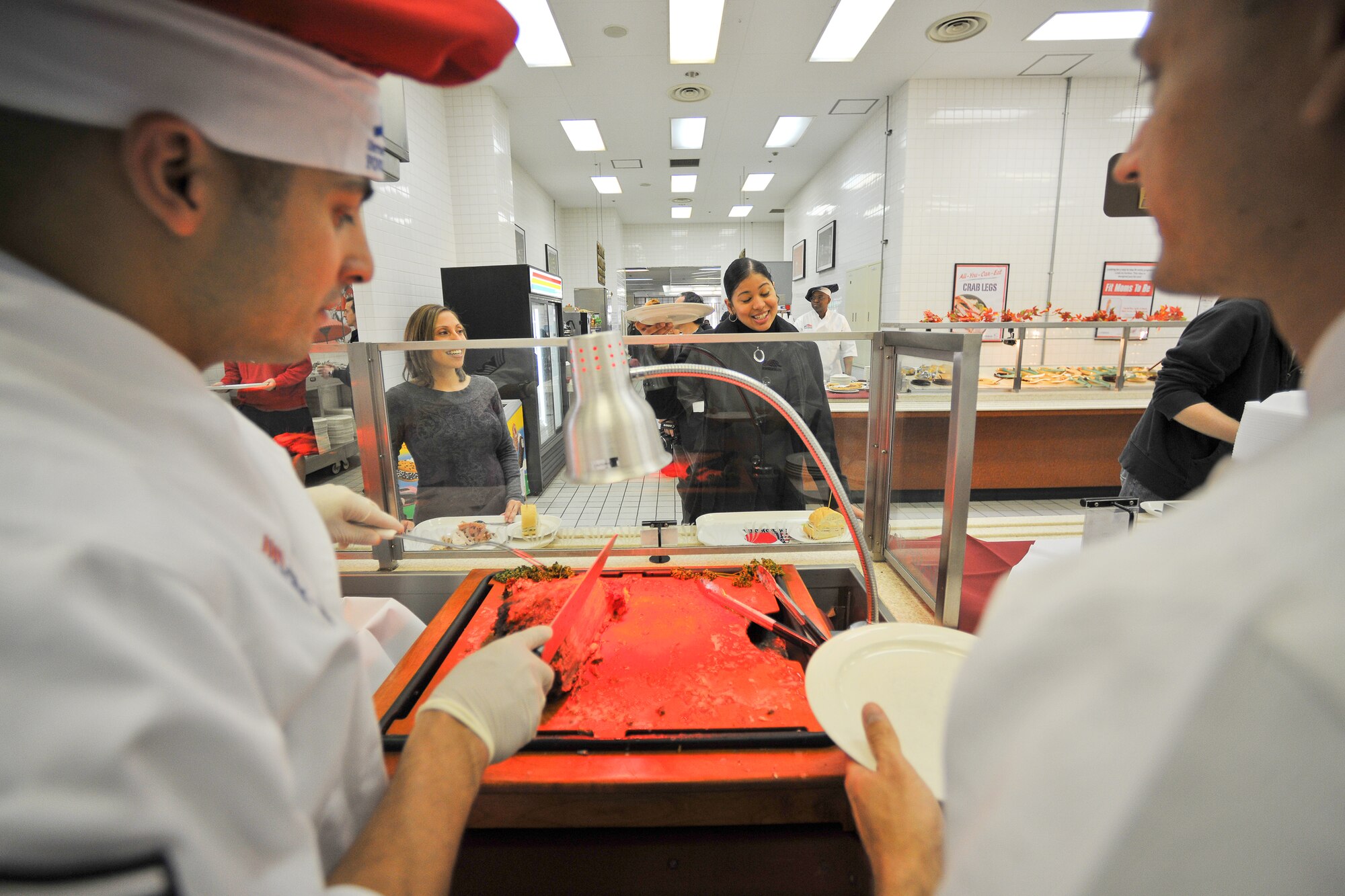 YOKOTA AIR BASE, Japan -- Senior Airman Hangie De Los Santos (center), 374th Force Support Squadron, asks for a piece of roast beef served by Command Chief Master Sgt. Benjamin Caro, Jr. (left), 374th Airlift Wing here Nov. 25 at the Samurai Cafe dining facility. (U.S. Air Force photo/Osakabe Yasuo)