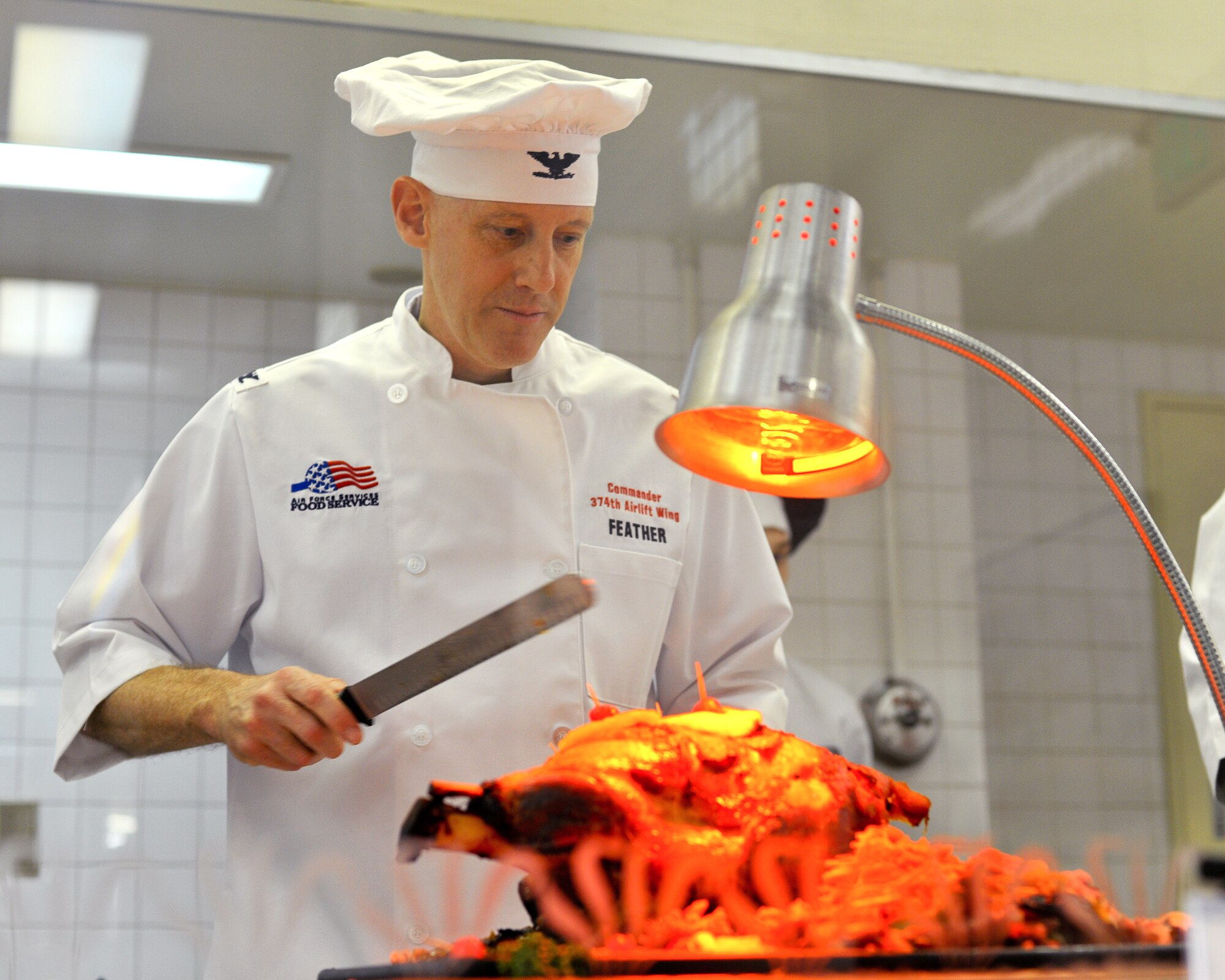 YOKOTA AIR BASE, Japan -- Yokota leaders serve a traditional thanksgiving meal Nov. 25 at Samurai Cafe dining facility. Col. Otto Feather, 374th Airlift Wing commander, carves the roast ham for the single service members and deployed families. (U.S. Air Force photo/Osakabe Yasuo)