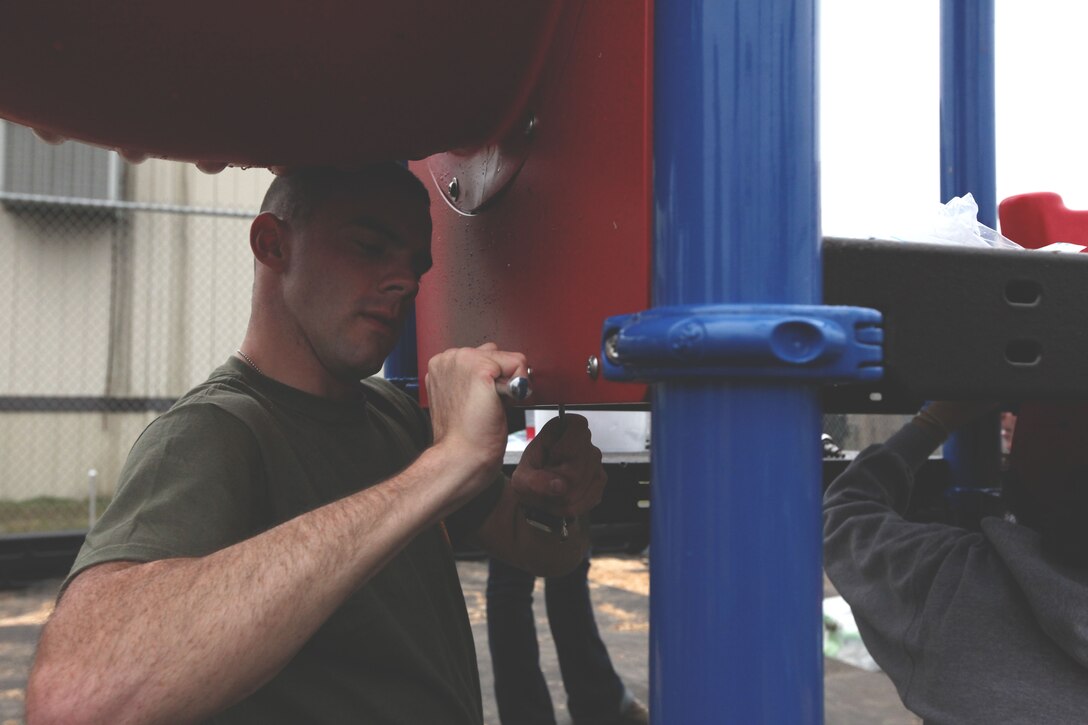 Cpl. Joel Bell, data network specialist, Marine Forces Reserve Headquarters tightens a bolt on part of the new playground at the Intercultural Charter School here Nov. 26.