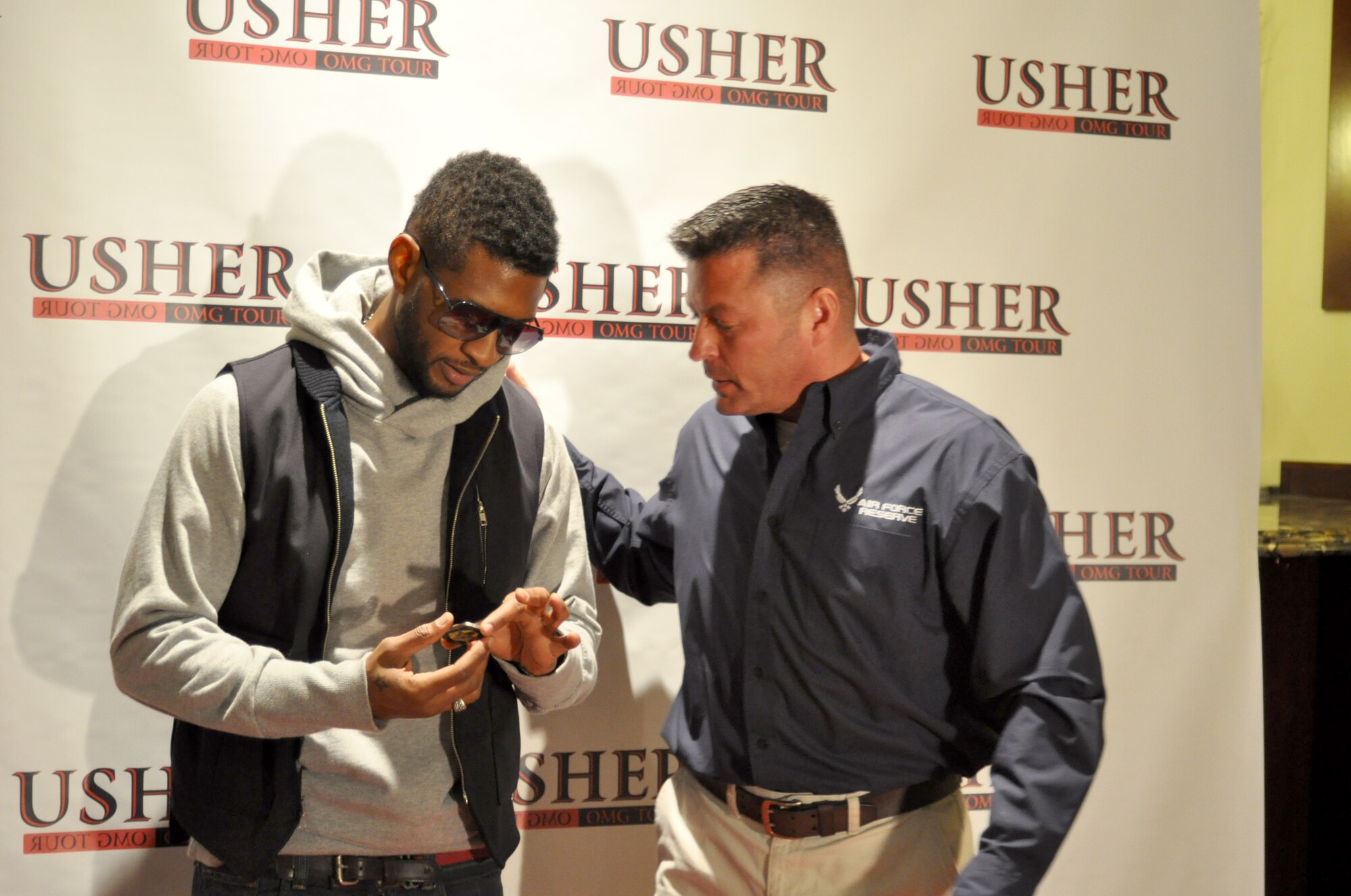 Lt. Col. Bryan Winter, Western Recruiting Squadron commander, presents a coin to Usher before his concert in Anaheim, Calif., Nov. 14. Reservists who submitted a referral to the Get One Now program were treated to a personal backstage meet and greet with the singer and two tickets to his performance.  (U.S. Air Force photo by Linda Welz)
