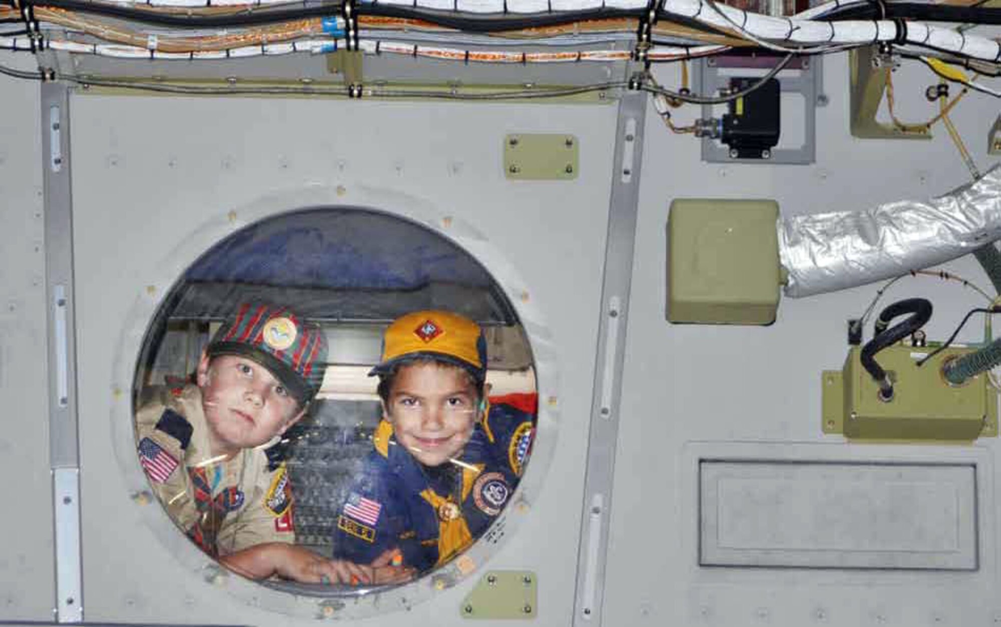 (from left) Cameron Nollar, a Weblo Scout, and his brother Tyler, a Wolf Scout, look out of the cargo compartment window in a C-17 Globemaster during a visit to the base. James Rich, a human resource specialist with the civilian personnel office, arranged the tour for fourteen scouts in his grandson’s Cub Scout Troop in Redlands, Calif.  (U.S. Air Force photo by Linda Welz)

