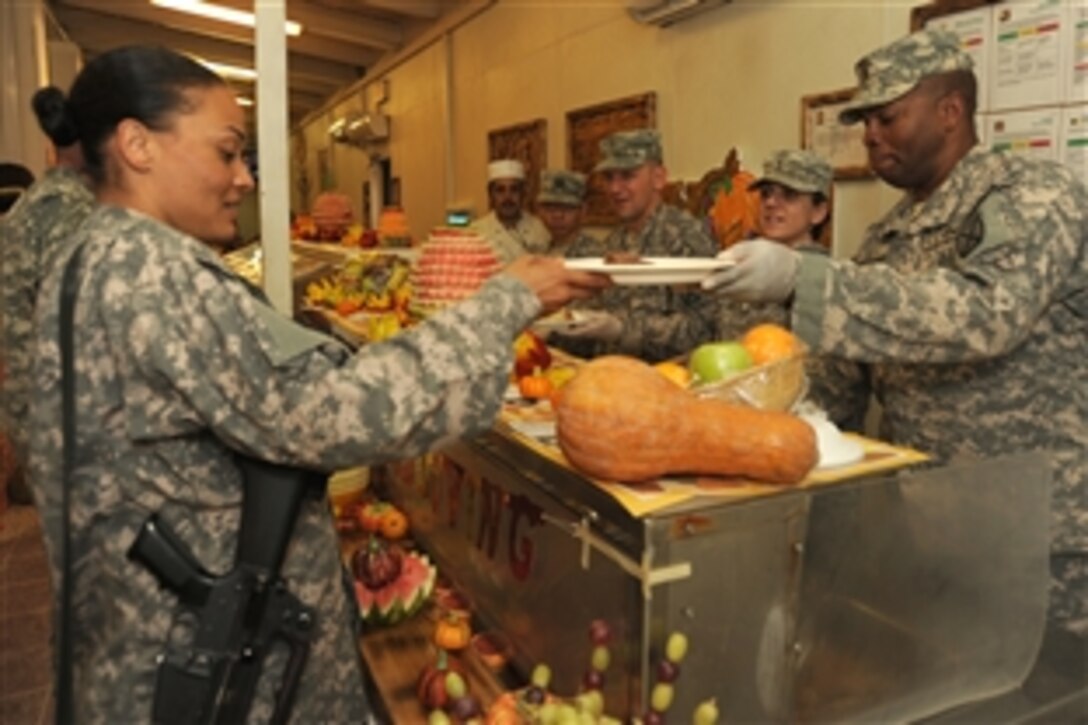 U.S. Army Sgt. Maj. David Shaw serves up a helping of turkey to Spc. Ariana Williams of the 1st Brigade, Special Troops Battalion, during the Thanksgiving Day celebration, Nov. 25, 2010, on Camp Mike Spann in Northern Afghanistan. Shaw is assigned to the Mountain Division’s, 1st Brigade Combat Team.