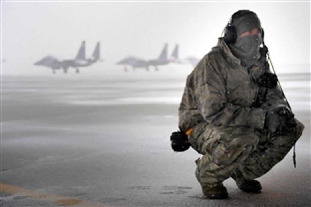 U.S. Air Force Senior Airman Stephen Held takes a break under an aircraft to hide from the snow during an exercise on the flight line at Mountain Home Air Force Base, Idaho, Nov. 21, 2010. Held, a crew chief, is assigned to the 391st Fighter Squadron.