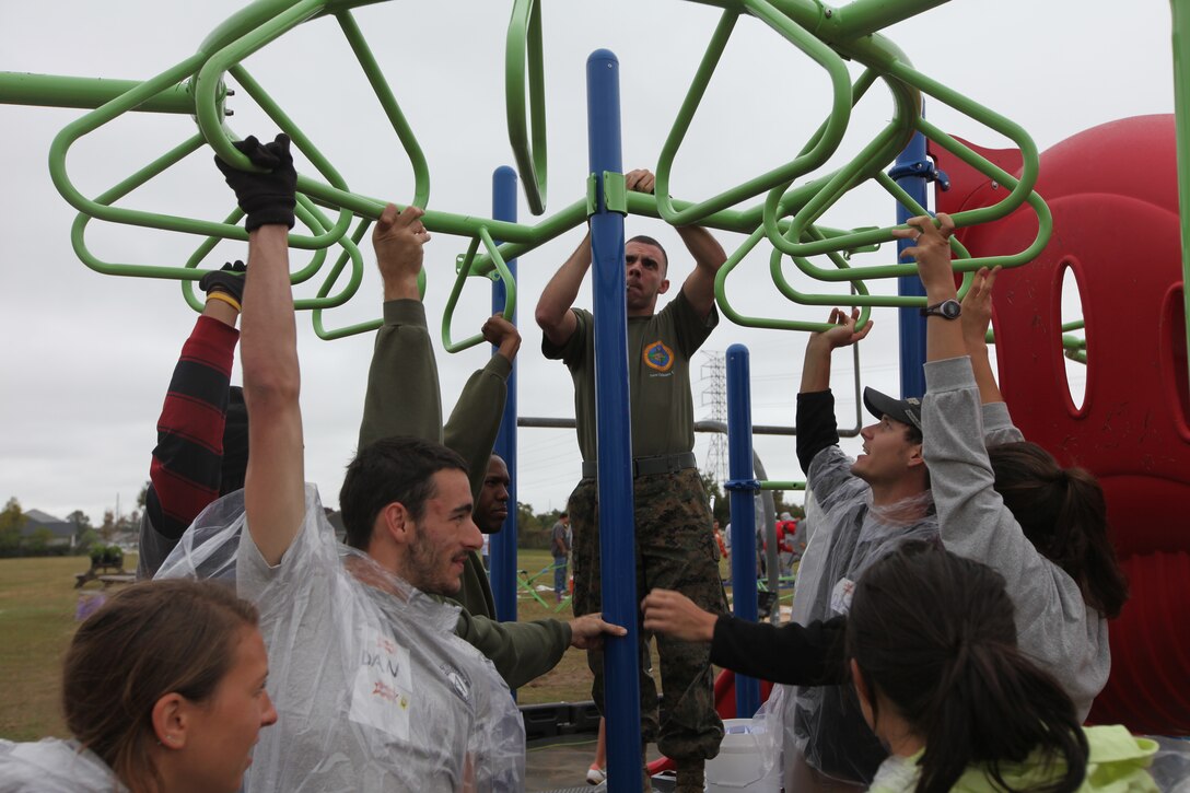 Volunteers hoist up monkey bars at the Intercultural Charter School in New Orleans East. Local volunteers teamed up with Marines from Marine Corps Recruiting Command and Marine Forces Reserve to build the playground Nov. 26.