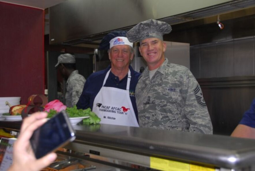 Chief Master Sergeant Sgt. Brooke McLean, Pacific Air Forces command chief, and Mr. Tom Ritchie, a Hawaii-based civic leader, pause for a photograph while serving a Thanksgiving meal Nov. 25 at the Gingko Tree dining facility, Osan Air Base, Republic of Korea. (U.S. Air Force photo/Staff Sgt. Eunique Stevens)