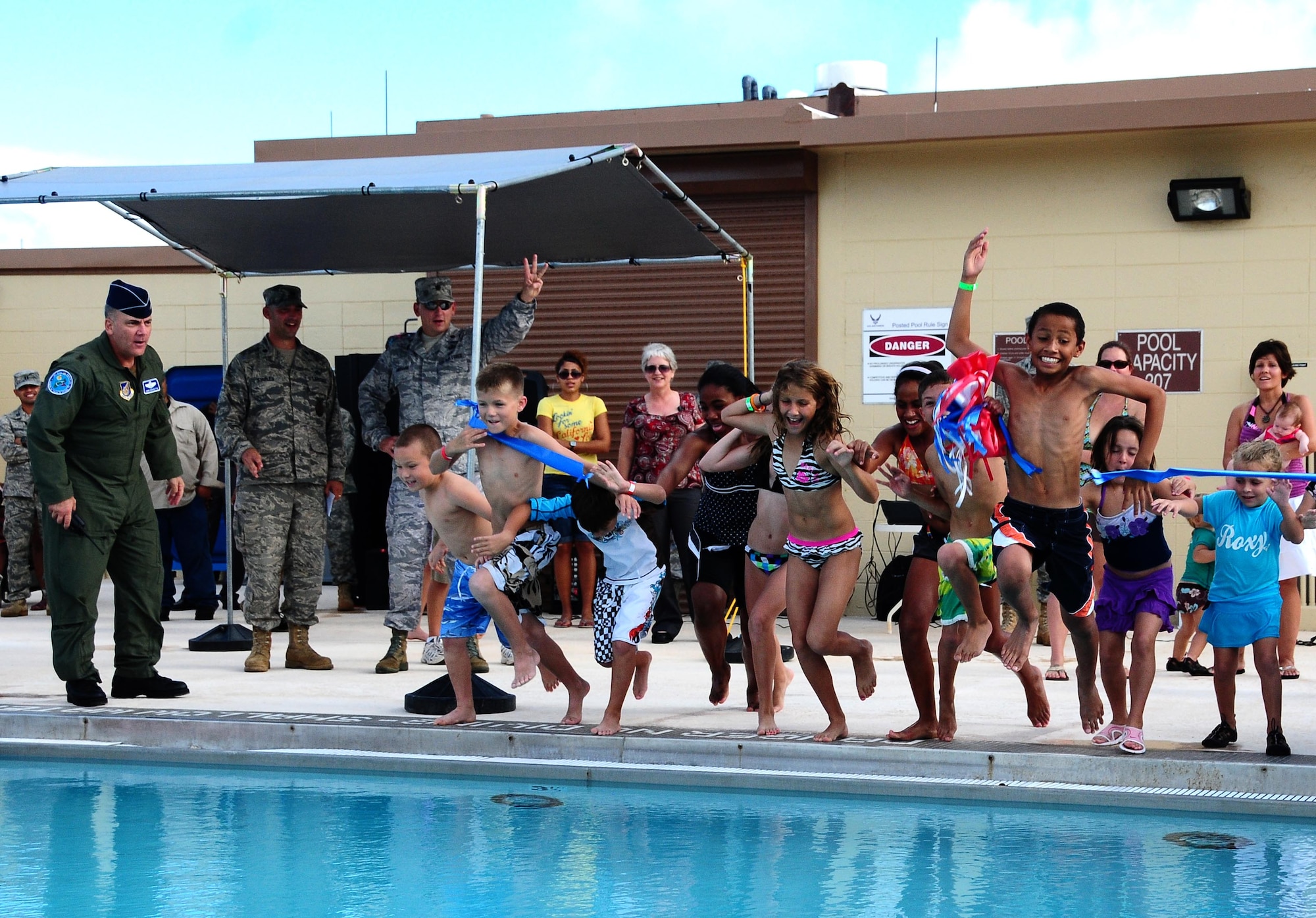 Brig. Gen. John Doucette, 36th Wing commander, looks on as Team Andersen children jump into the Andersen Air Force Base pool at the grand re-opening here Nov. 24. The pool reopened after undergoing more than a year of substantial renovations. (U.S. Air Force photo/Airman 1st Class Jeffrey Schultze)