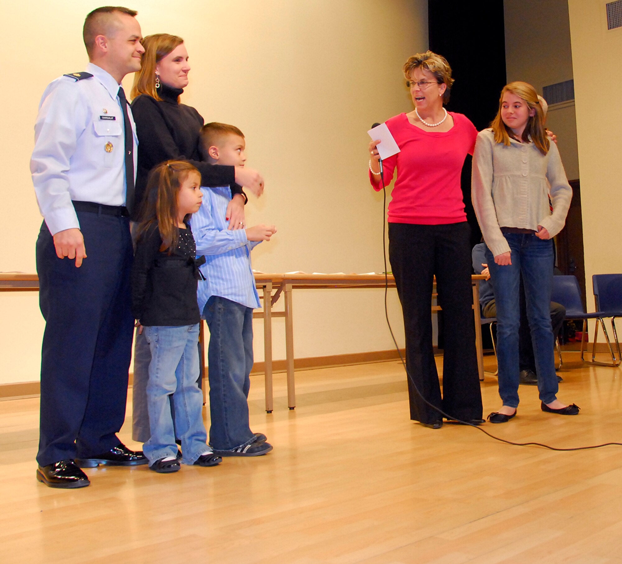 Maggie Dene, a ninth-grade student at Osan American High School, right, stands with Carol Malackowski as the Chargualaf family, left, looks on during an awards ceremony at the school Nov. 22. Maggie was reconnized at the ceremony for demonstrating “Extraordinary Personal Action” while baby-sitting for the family Oct. 2. (U.S. Air Force photo/Staff Sgt. Eunique Stevens)