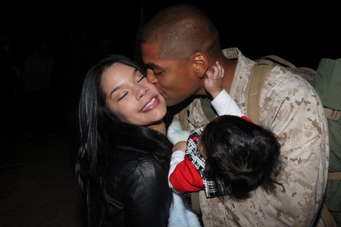 201029-M-9595T-134::r::::n::Cpl. Cesar Rojas, Battery L, 3rd Battalion, 12th Marines, kisses his wife Arielis Rojas, while holding his 5-month-old son Gabriel during a homecoming celebration at Del Valle Field at the Marine Corps Air Ground Combat Center, Twentynine Palms, Calif., Nov. 29. Rojas is meeting his son Gabriel for the first time. Gabriel, who his mother describes as just active and "exactly" like his father, was born in June, a month after Rojas deployed.